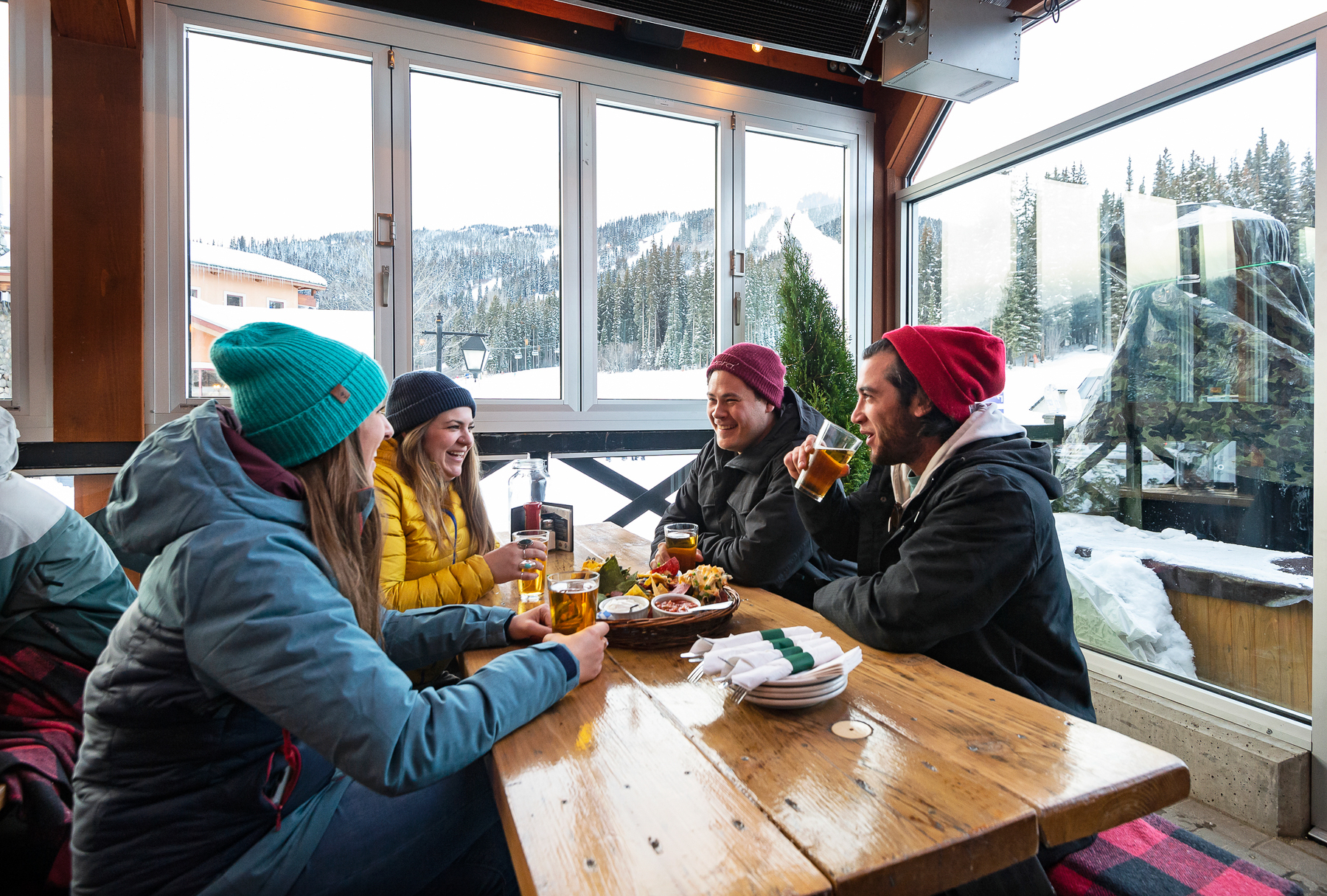 Four people sitting around a table in a bar with mountain views in the background