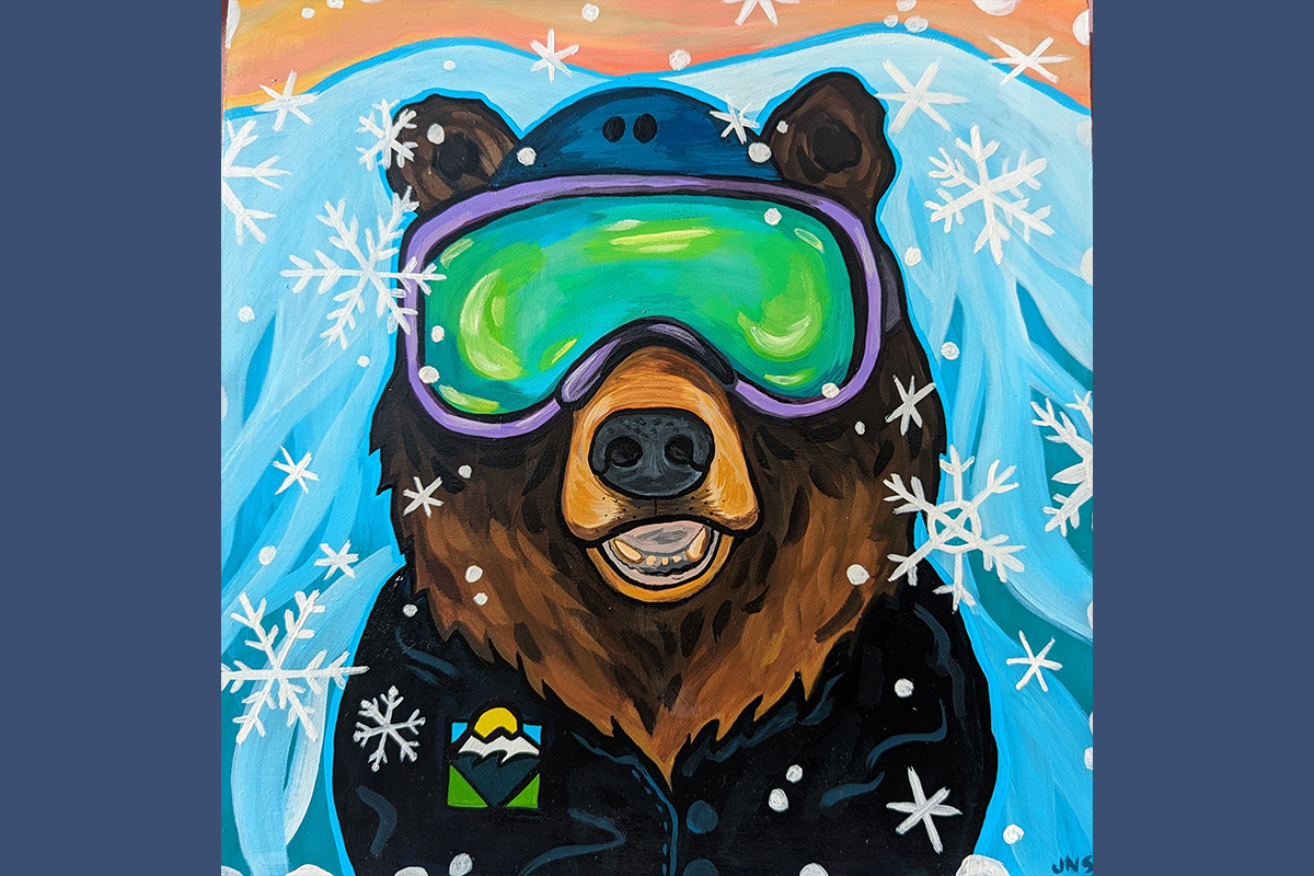 A bear wearing ski goggles, standing in front of a blue mountain background