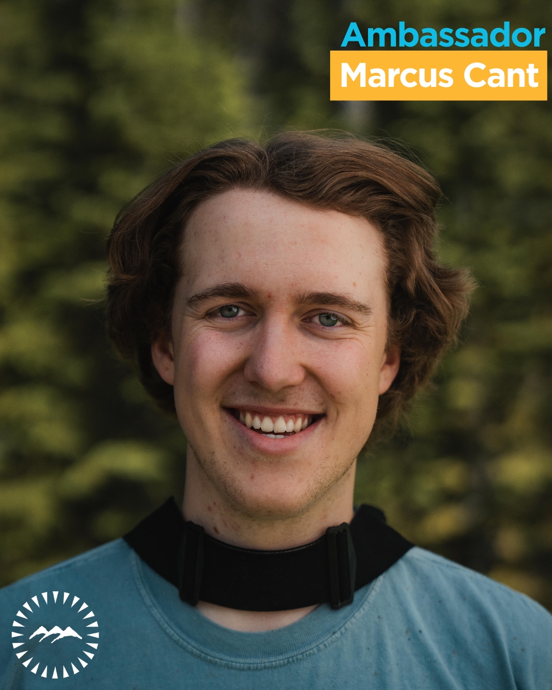 man smiling at the camera with greenery behind him