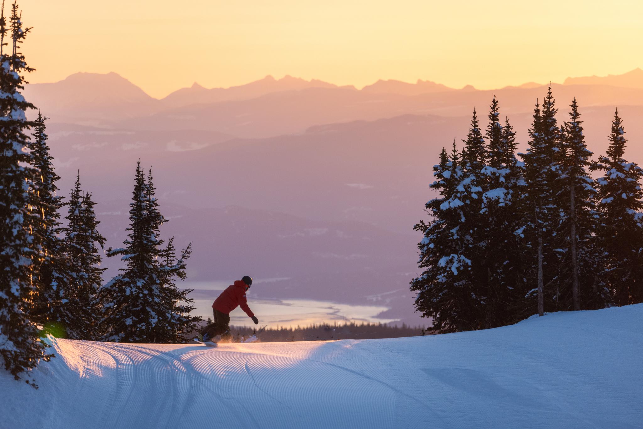 Snowboarder riding alpine terrain in sun peaks in spring conditions