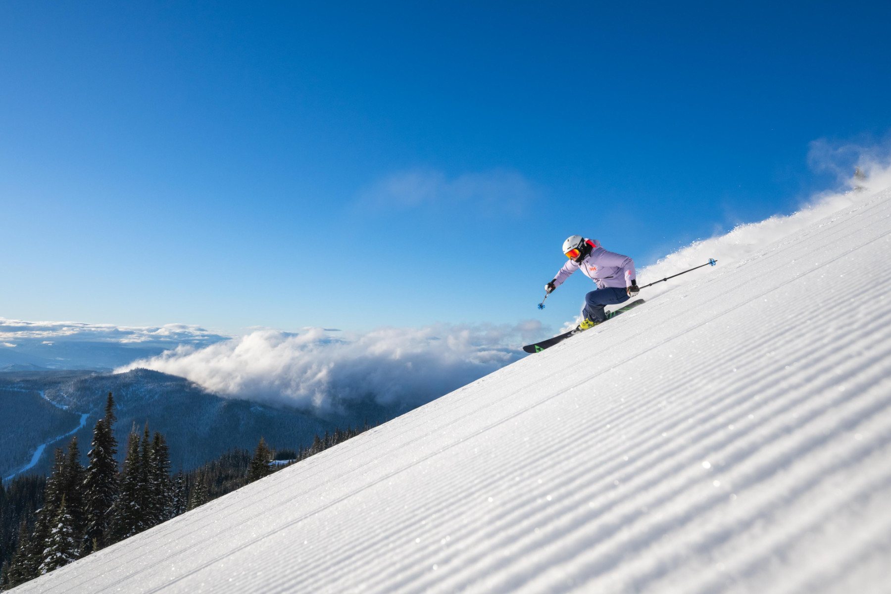 Skier riding down powder with blue skies behind them