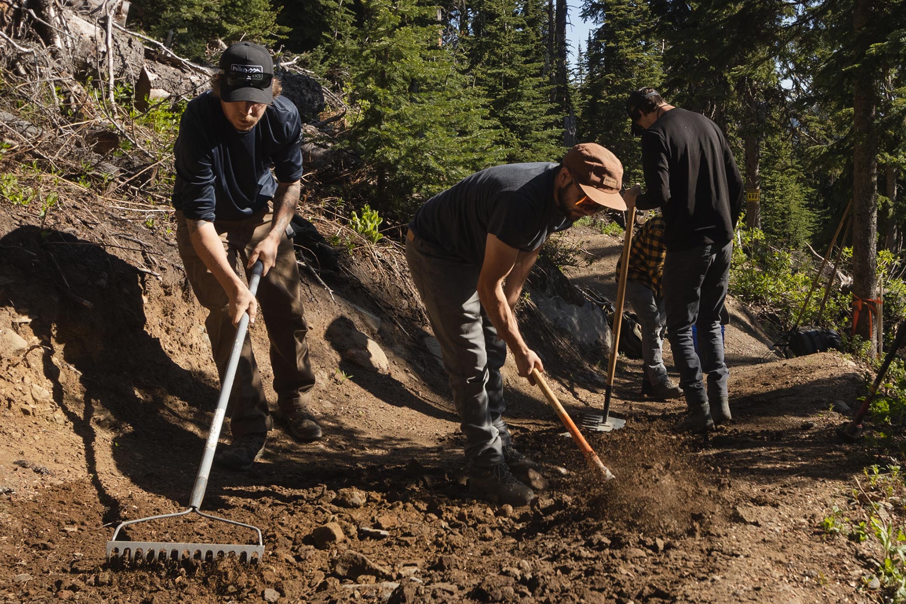 Three trail crew members working on a bike trail