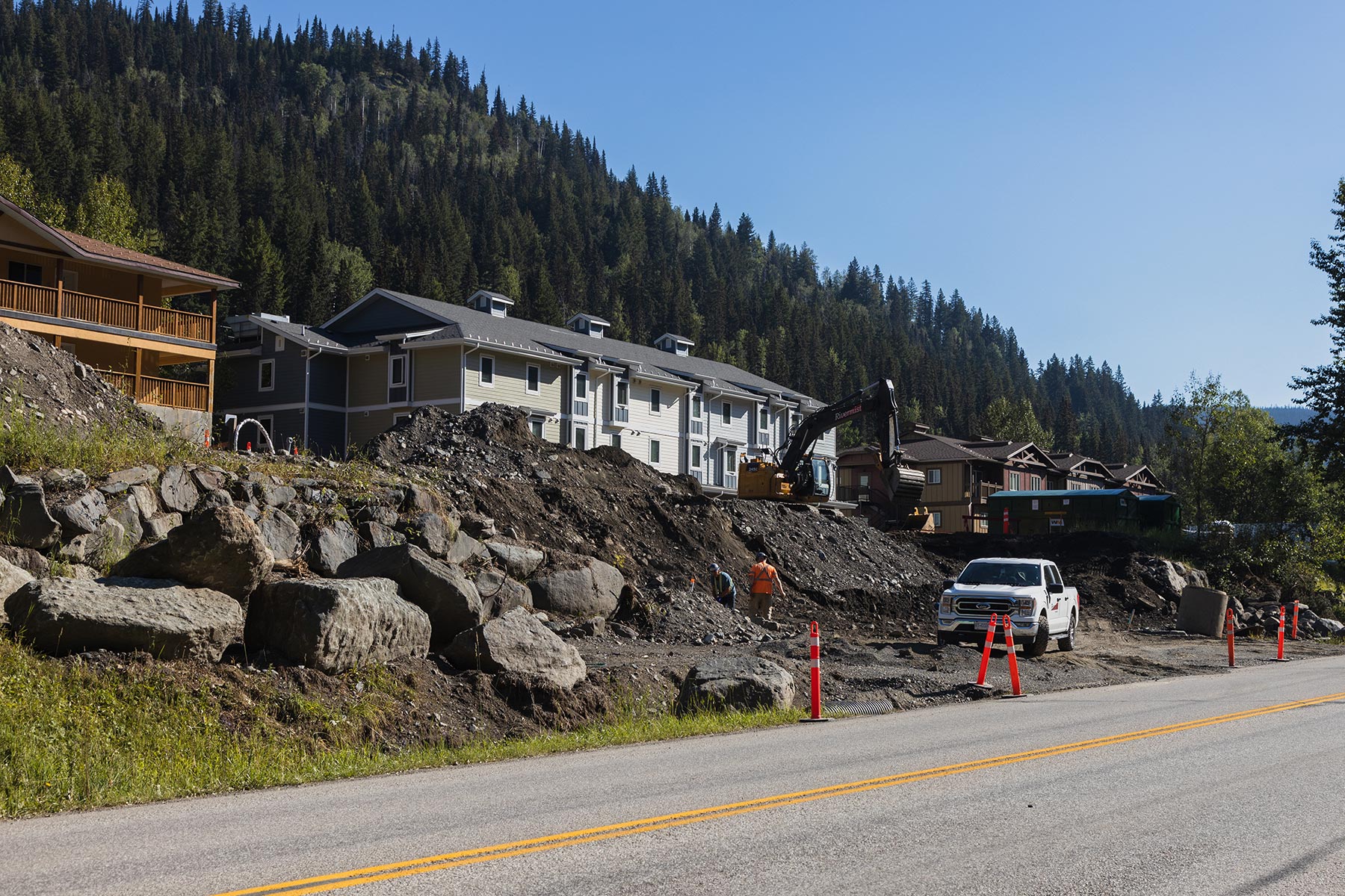 Excavator constructing new building foundations, with existing staff accommodation buildings in background.