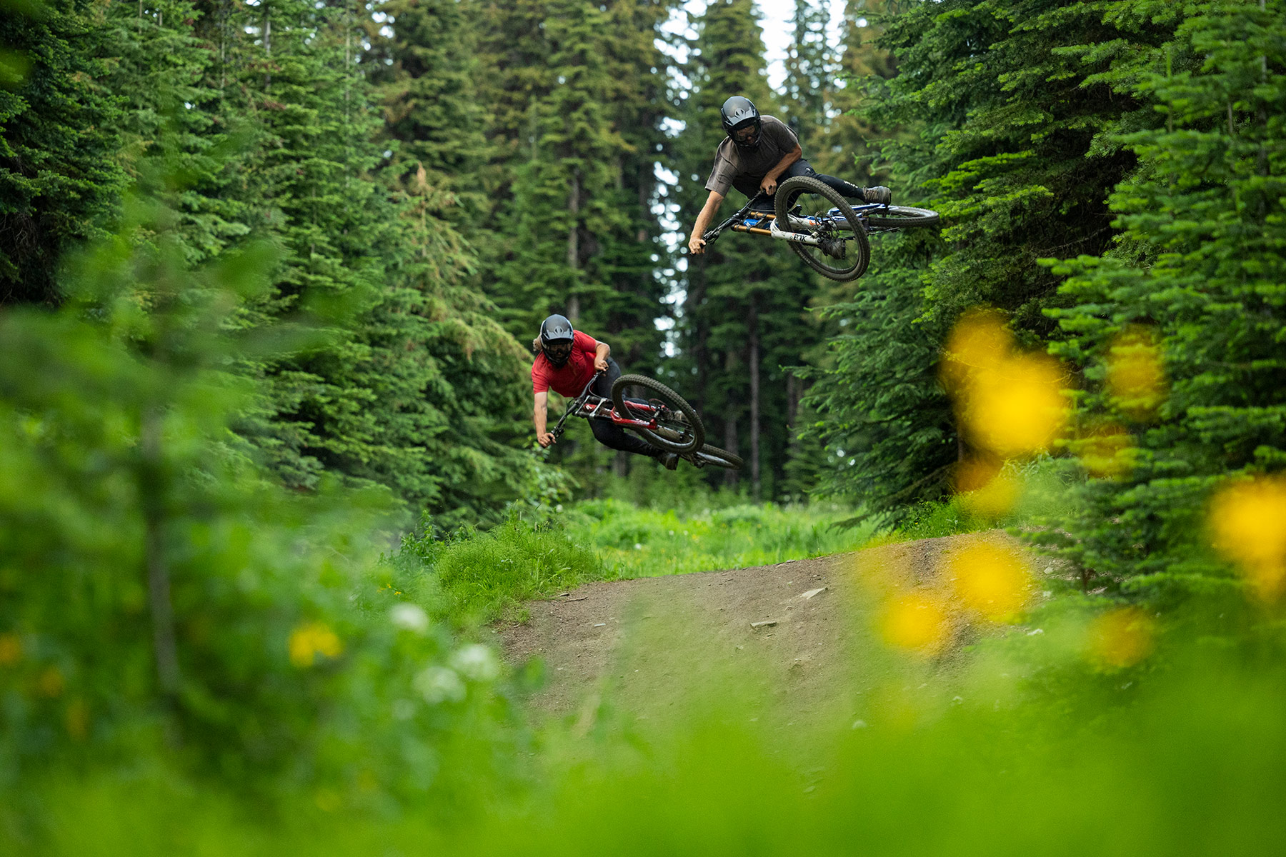 Two mountain bikers jumping in the Sun Peaks Bike Park