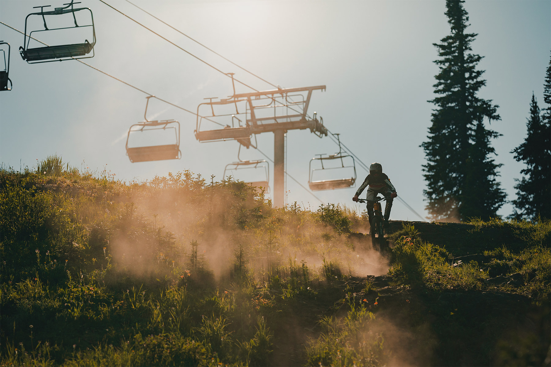 Mountain biker riding down a trail with chairlift in background