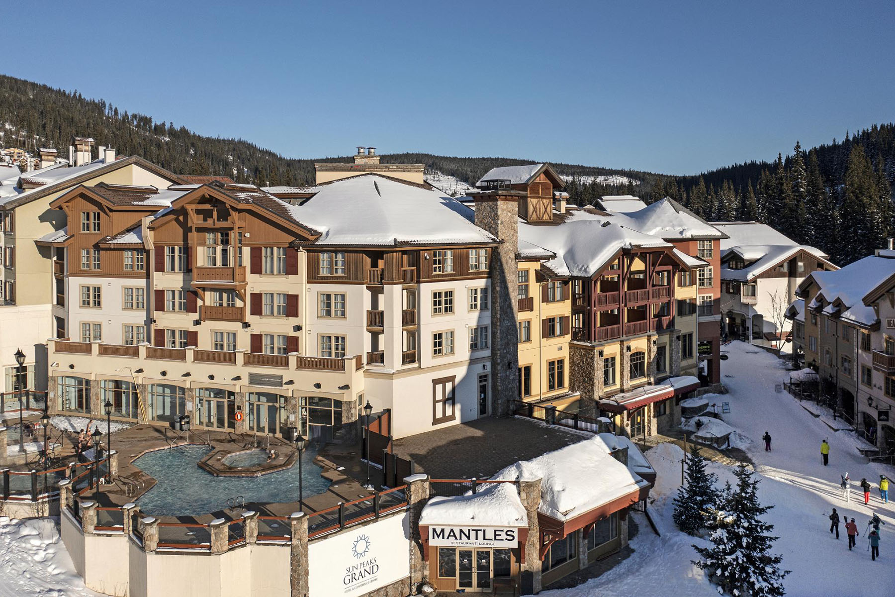Sun Peaks Grand Hotel aerial photo with skiers walking through village stroll