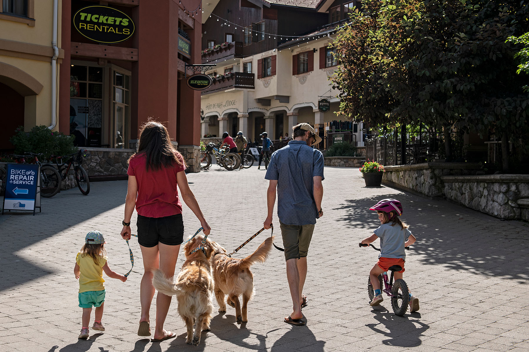 Family strolling sun peaks village with dogs and kids