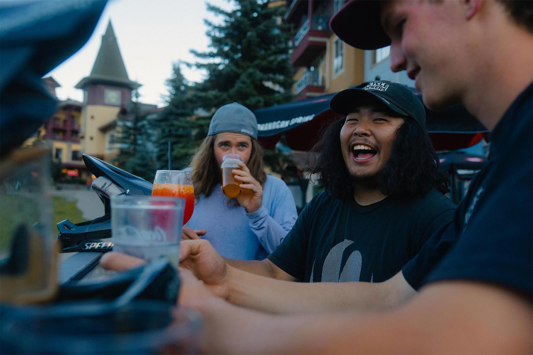Three boys sitting on a patio drinking and laughing