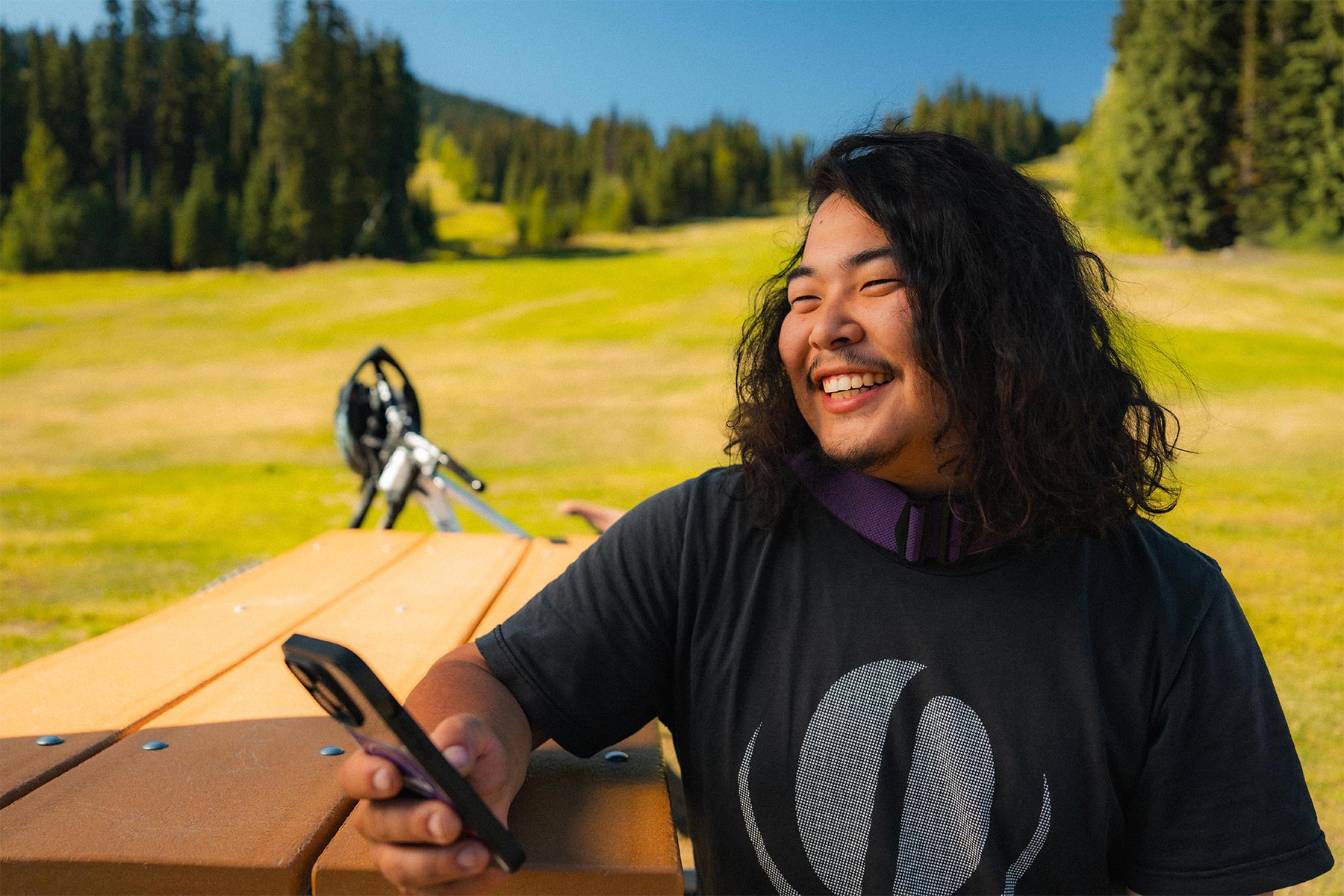 Man smiling at his phone with green behind him 