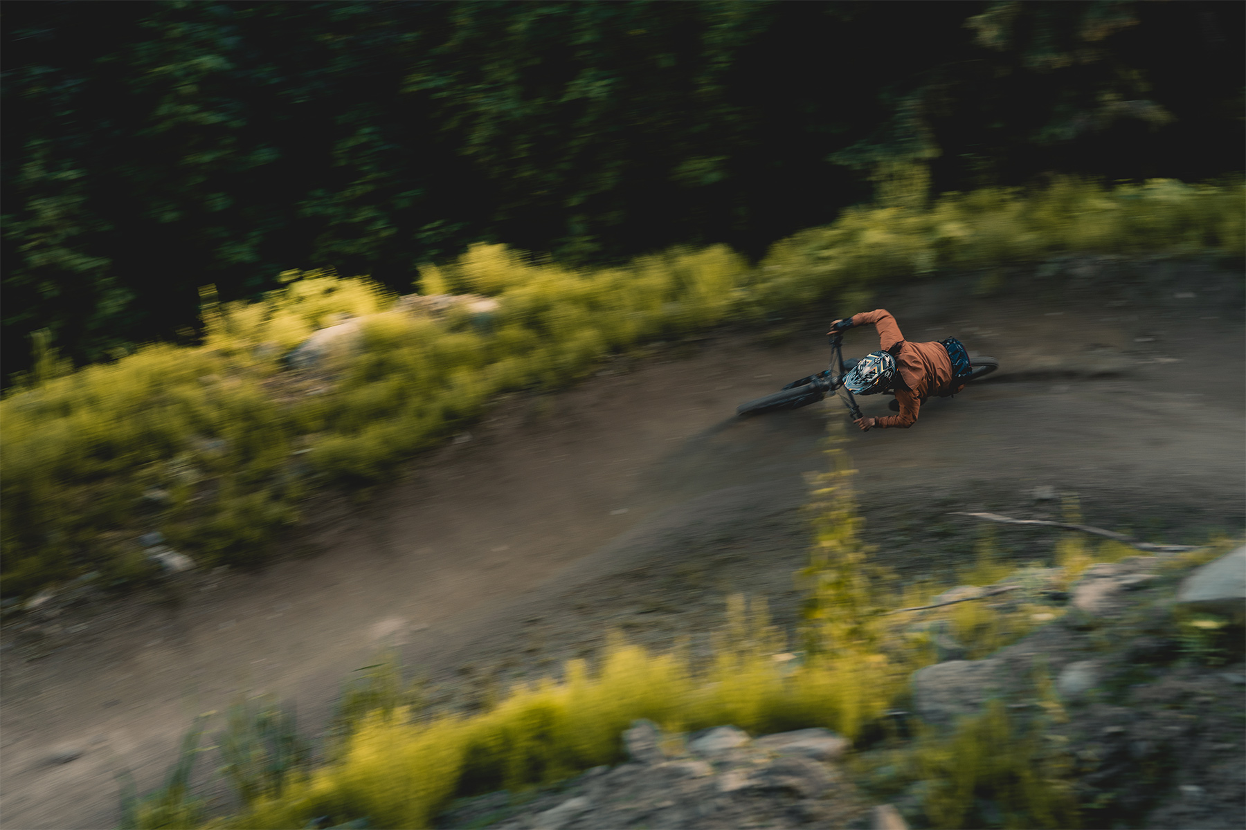 Mountain biker riding quickly down single track trail where the surrounding greenery is blurred