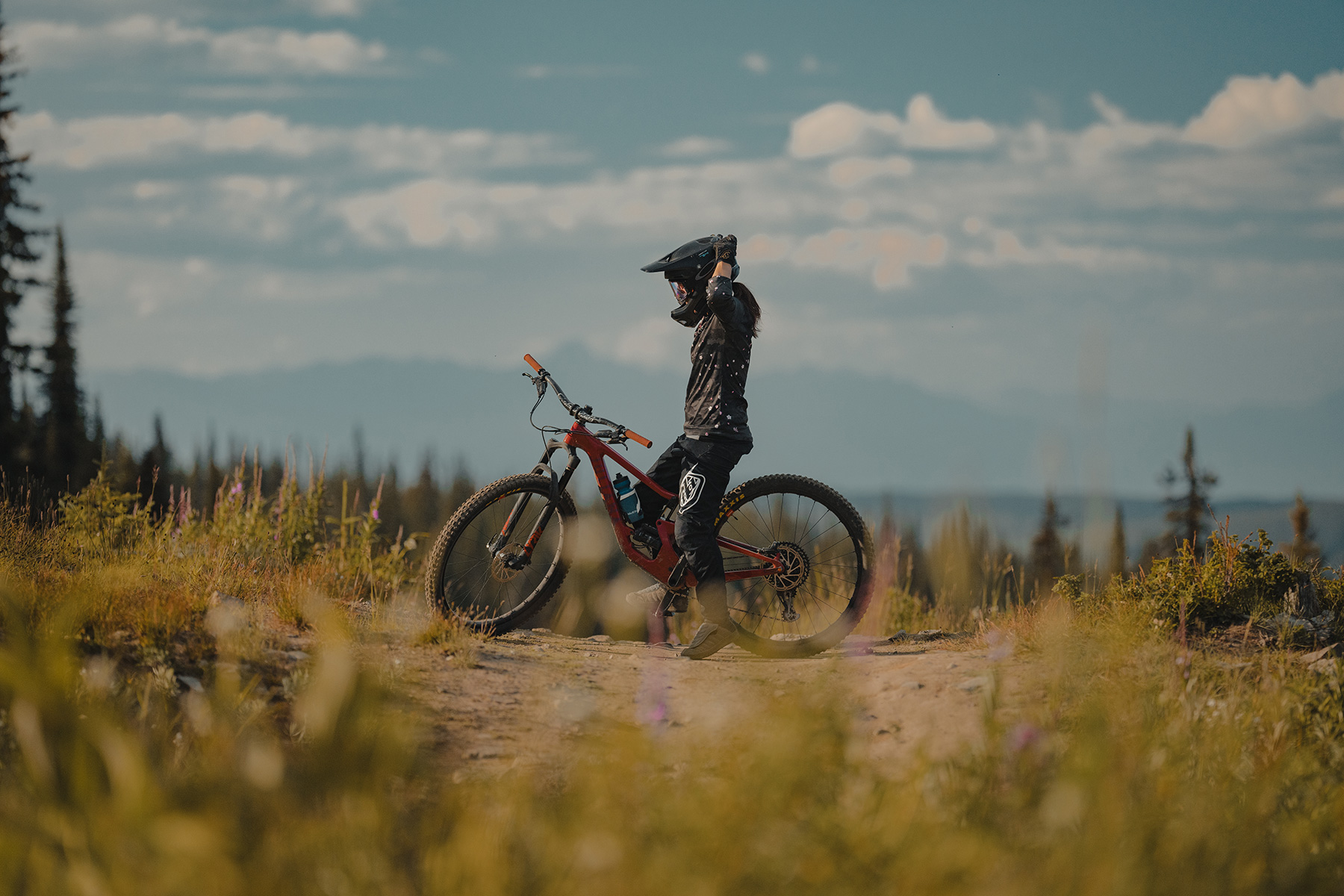 Kelly Kozevnikov adjusting goggles and helmet with mountain scenery in background