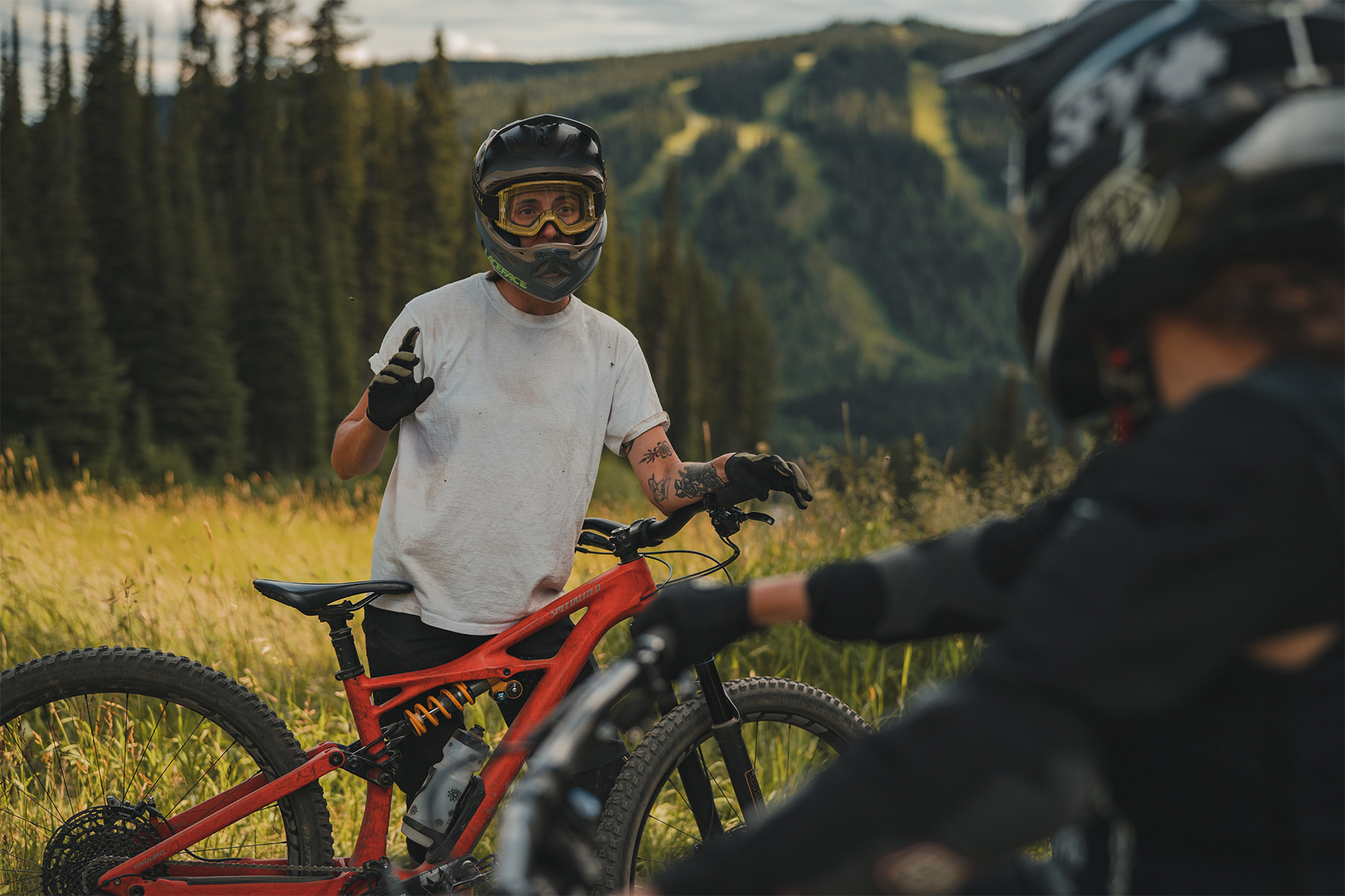 Two mountain bikers talk through full face helmets and goggles with Mnt.Morrisey in the background