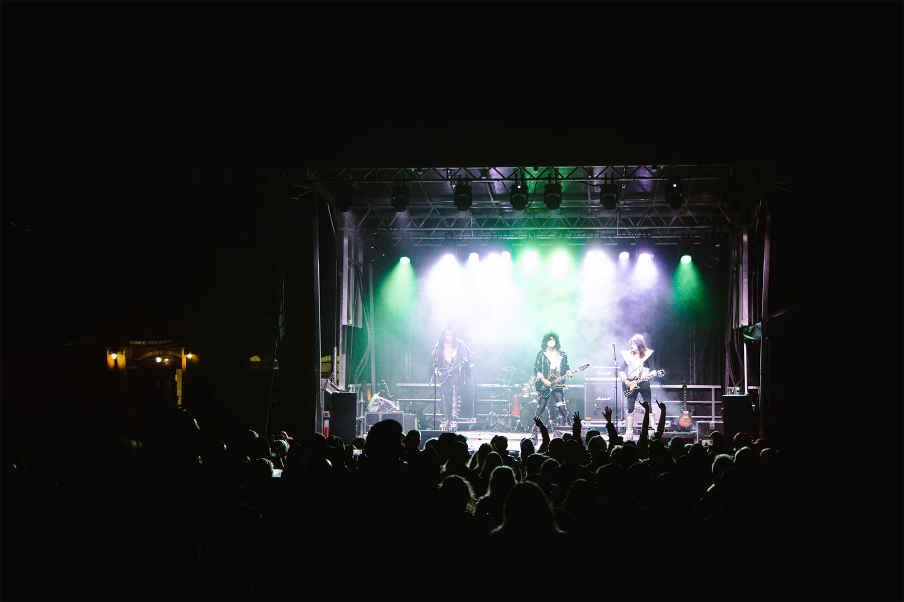 80s glam rock cover band performing in front of a dark crowd at night.