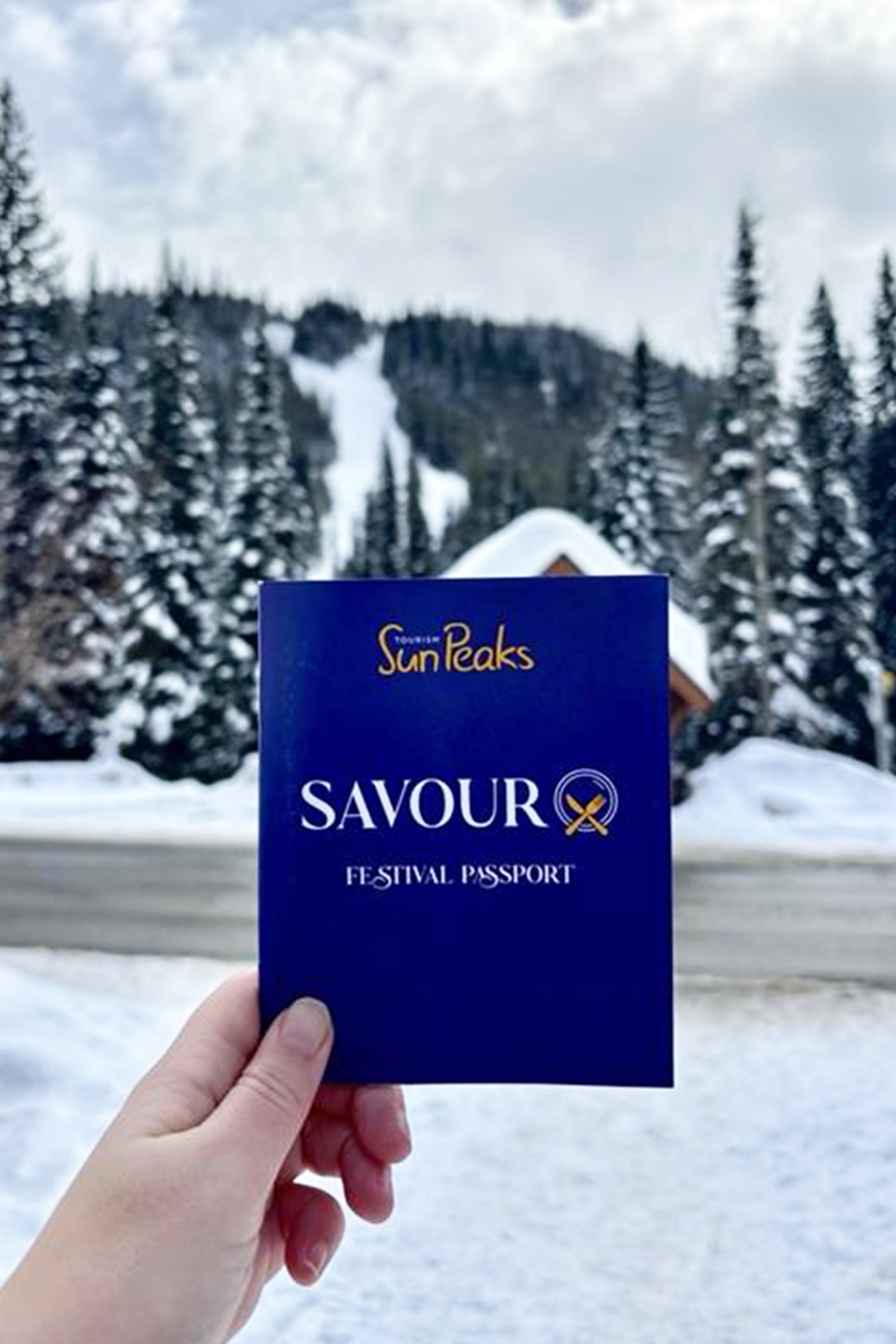 Savour Passport by Tourism Sun Peaks in front of snowy winter scene with trees.
