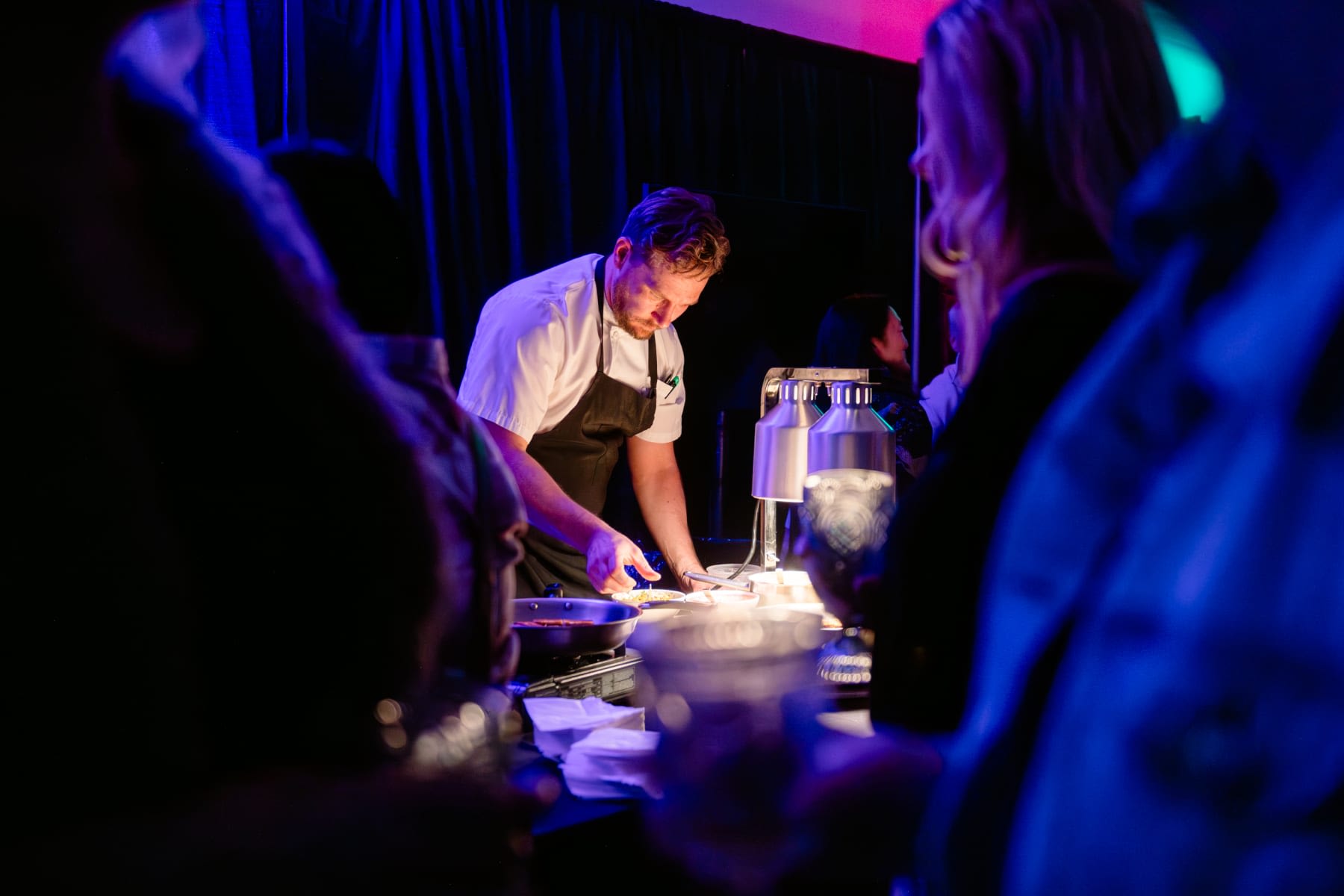 Chef Ryan Byrne preparing a dish at Epicurean in Sun Peaks BC. Dark purple party lighting.