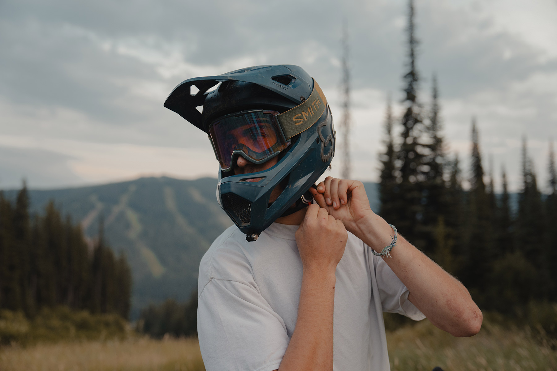 A man fastens the chin strap on his full face mountain bike helmet.