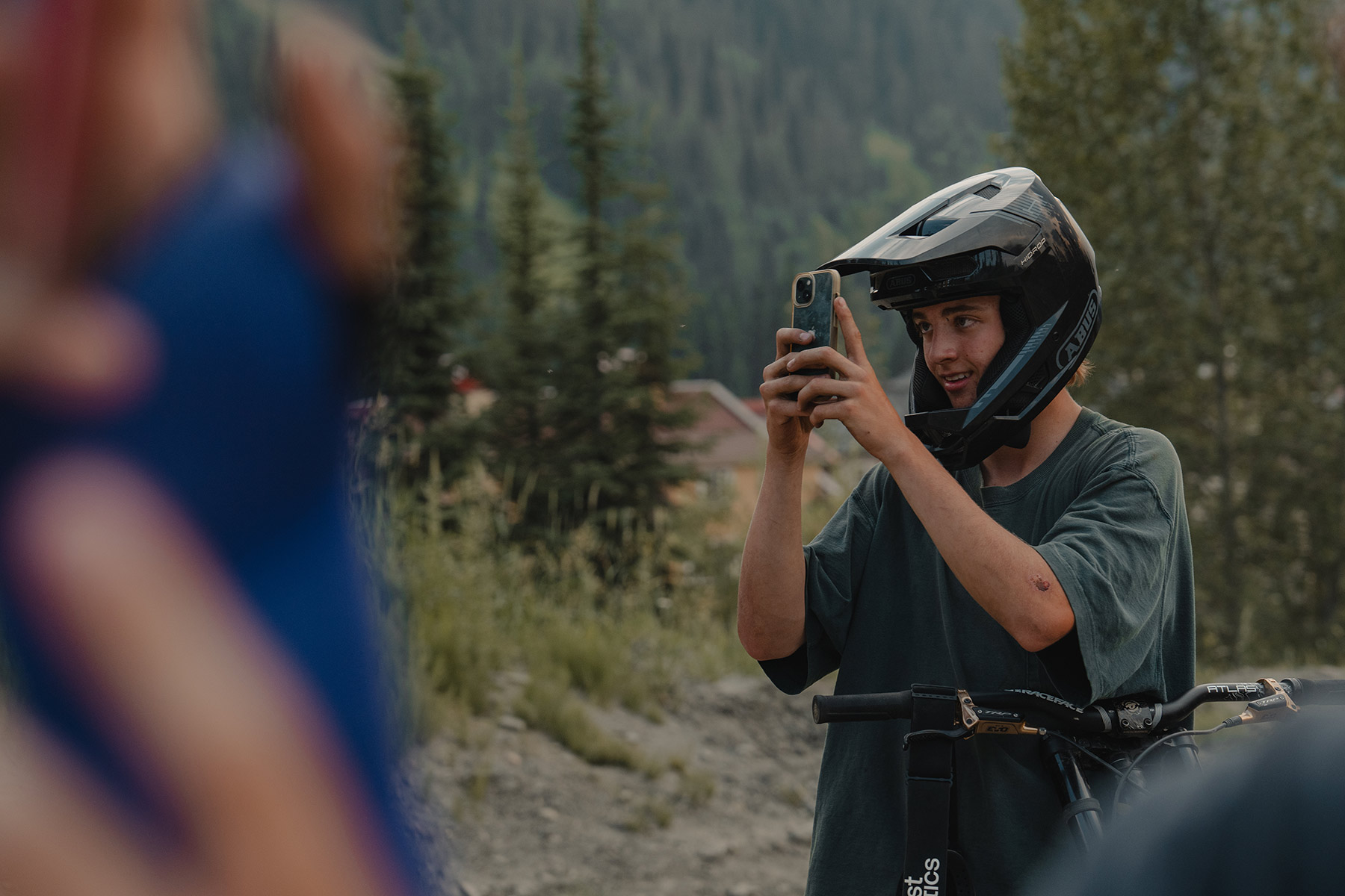 A mountain biker holds his iPhone up to record a fellow rider.