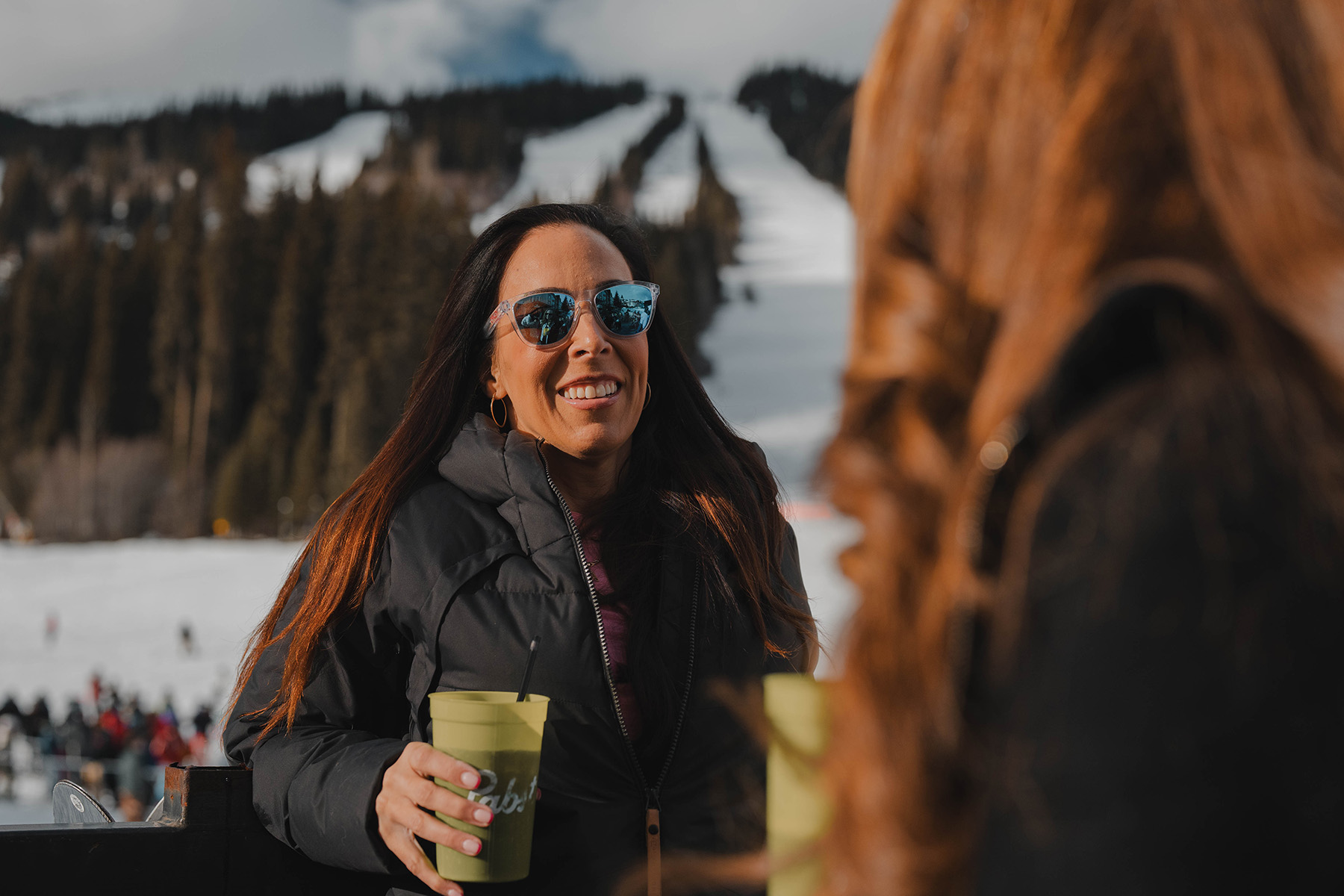 woman in sunglasses with beer on bottoms patio at sun peaks