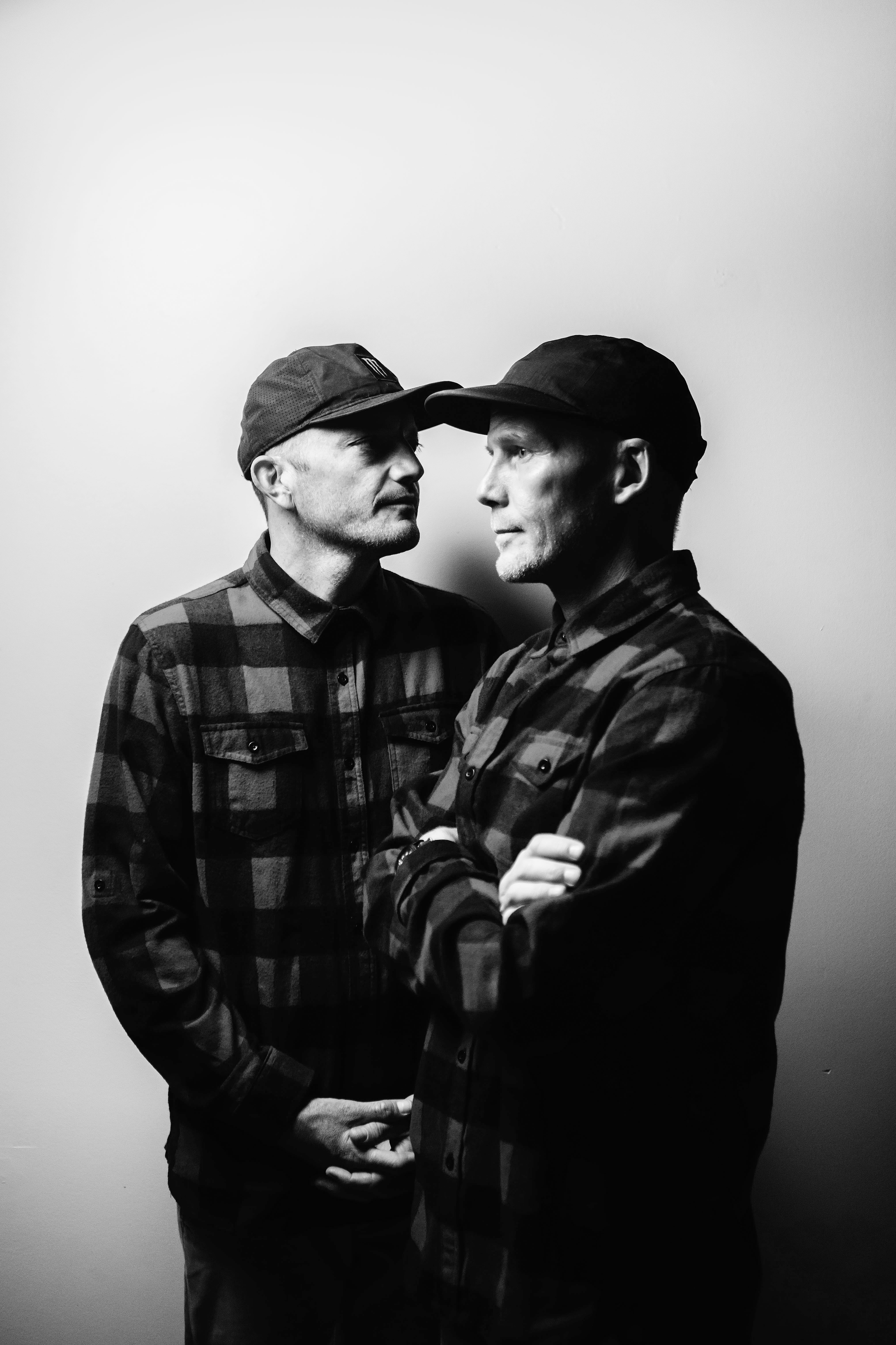 Smalltown Djs. Two men in plaid shirts, one looking to the left and the other to the right. Black and white tones.