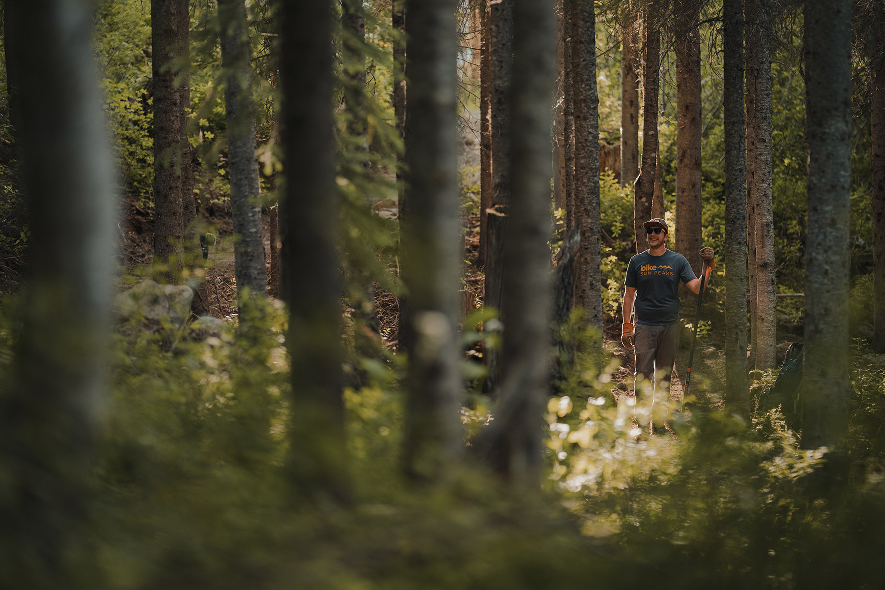 Volunteer standing with rake on a bike trail
