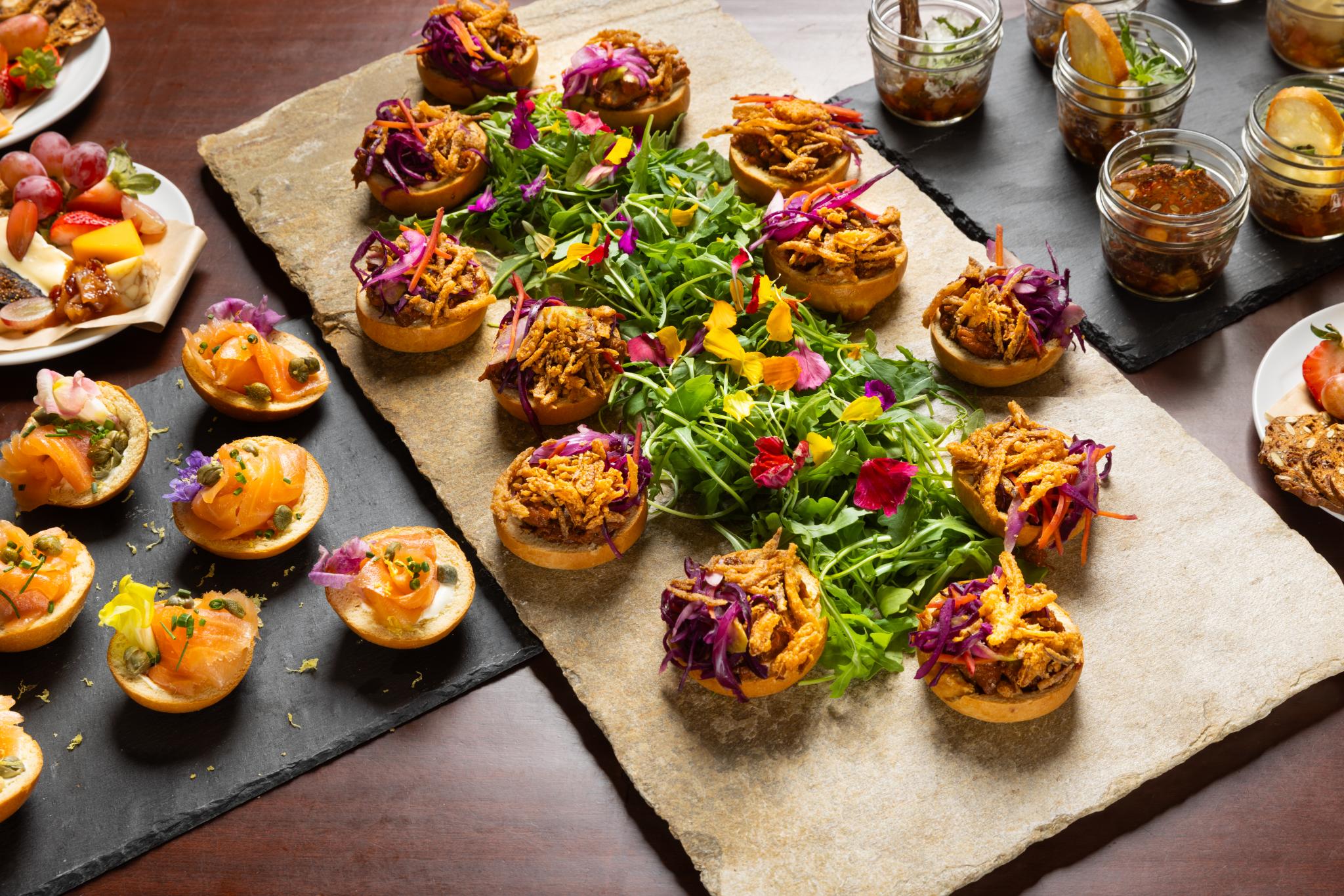Appetizers laid out on a tray, surrounding a green salad with colourful edible flowers.