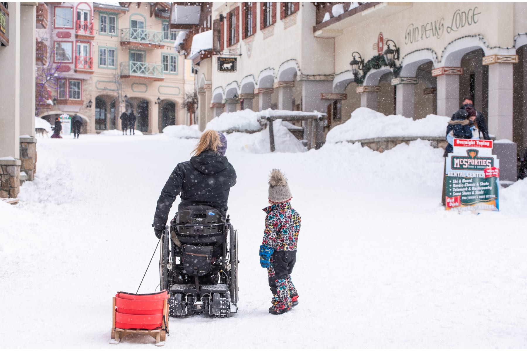 Woman in wheelchair with toddler standing in the Sun Peaks Village Stroll