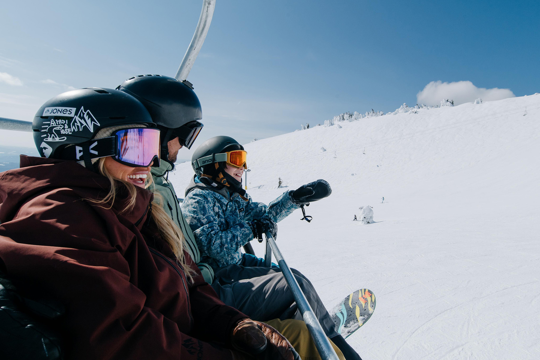 Smiling family riding the Crystal chairlift in Sun Peaks