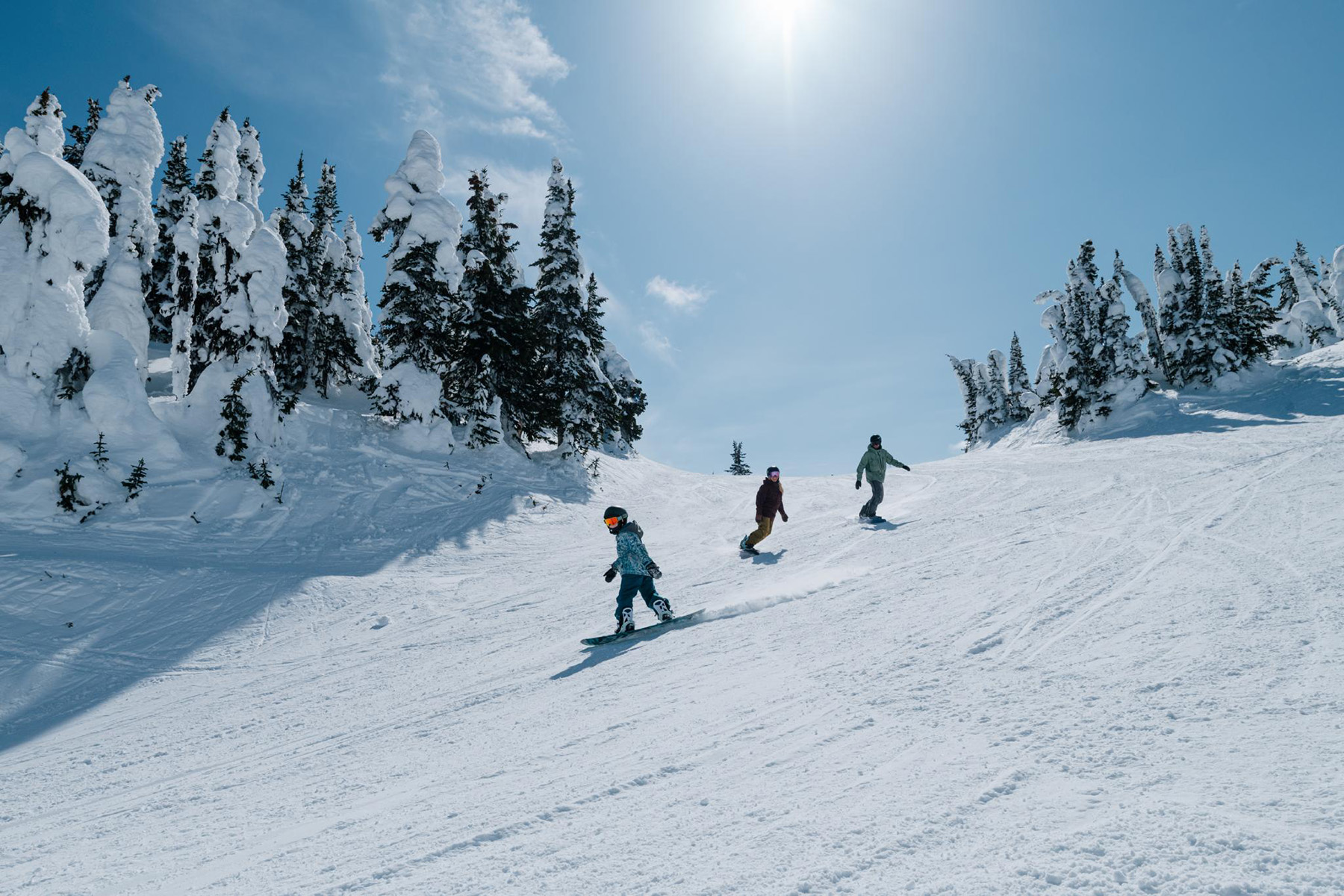 family snowboarding in sunshine at sun peaks