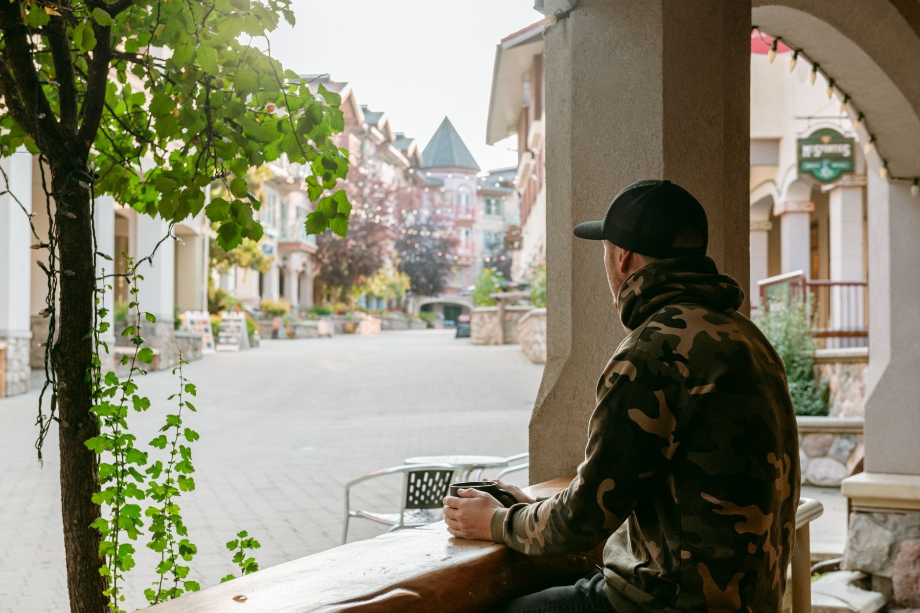 Kirk drinks a coffee at Tod Mountain Café in fall, looking out over Sun Peaks village.