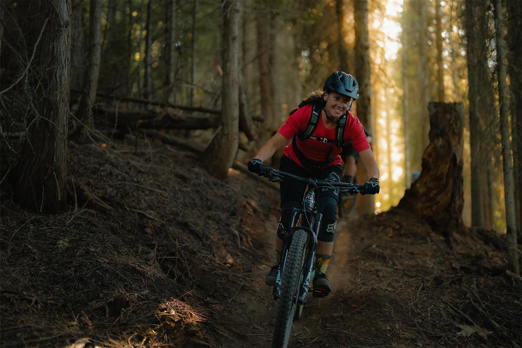 Woman biking on a trail surrounded by trees