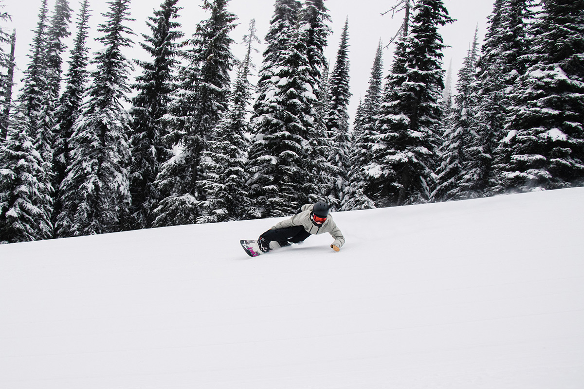 Snowboarder, Zuzy Rocka, gets low on a toe-side carve on a groomed run.