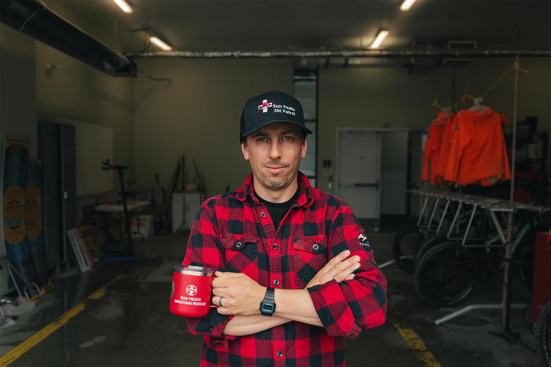 Man standing infront of the camera holding a coffee cup with his arms crossed