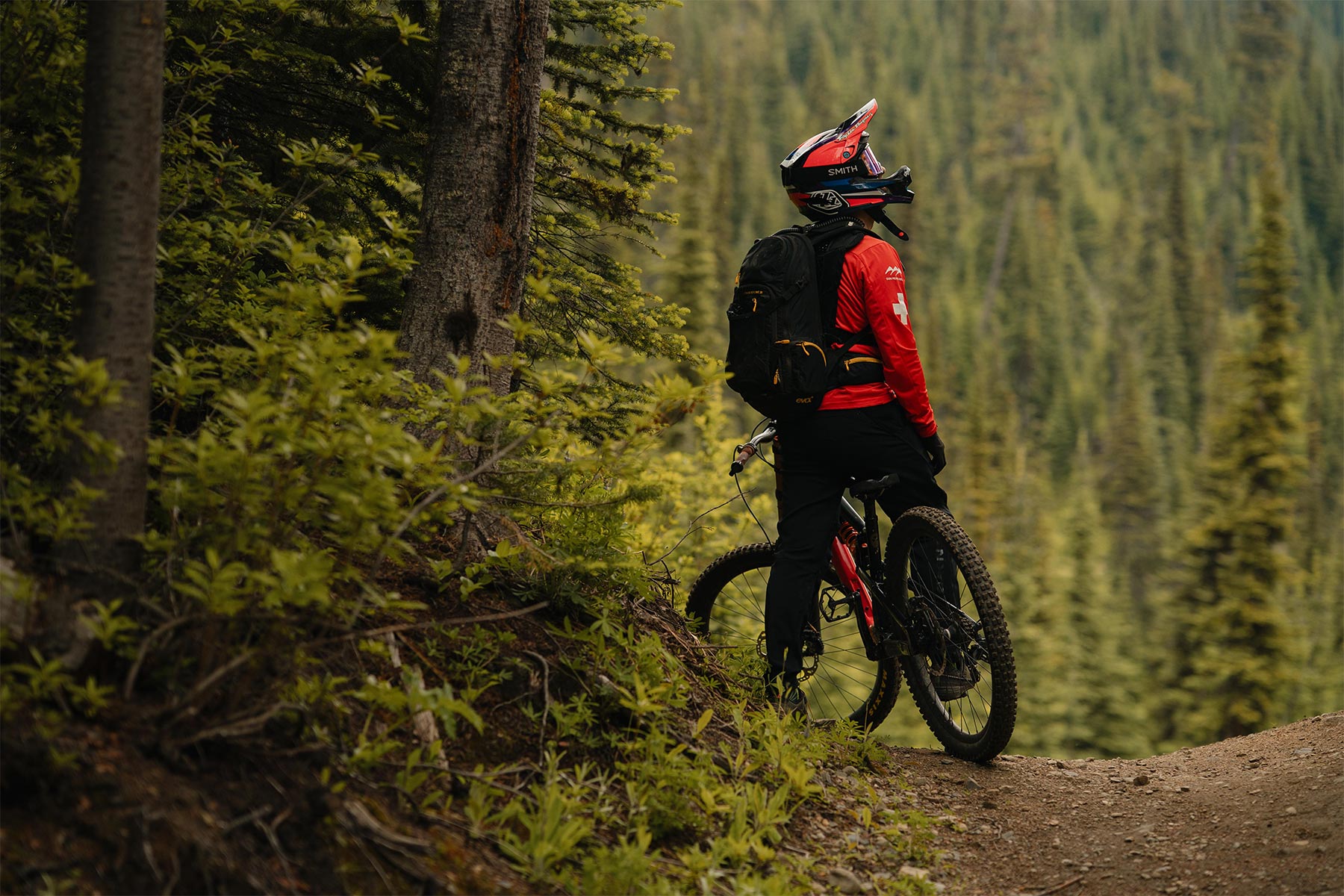 Man standing on his bike looking forward with trees around him.