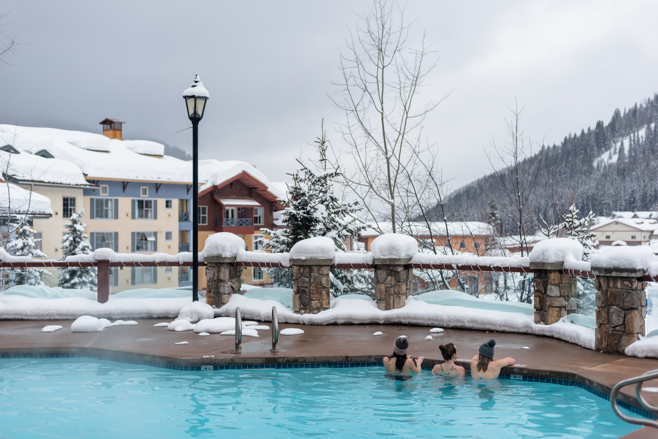 Three people leaning over the edge of the warm pool at the Sun Peaks Grand Hotel