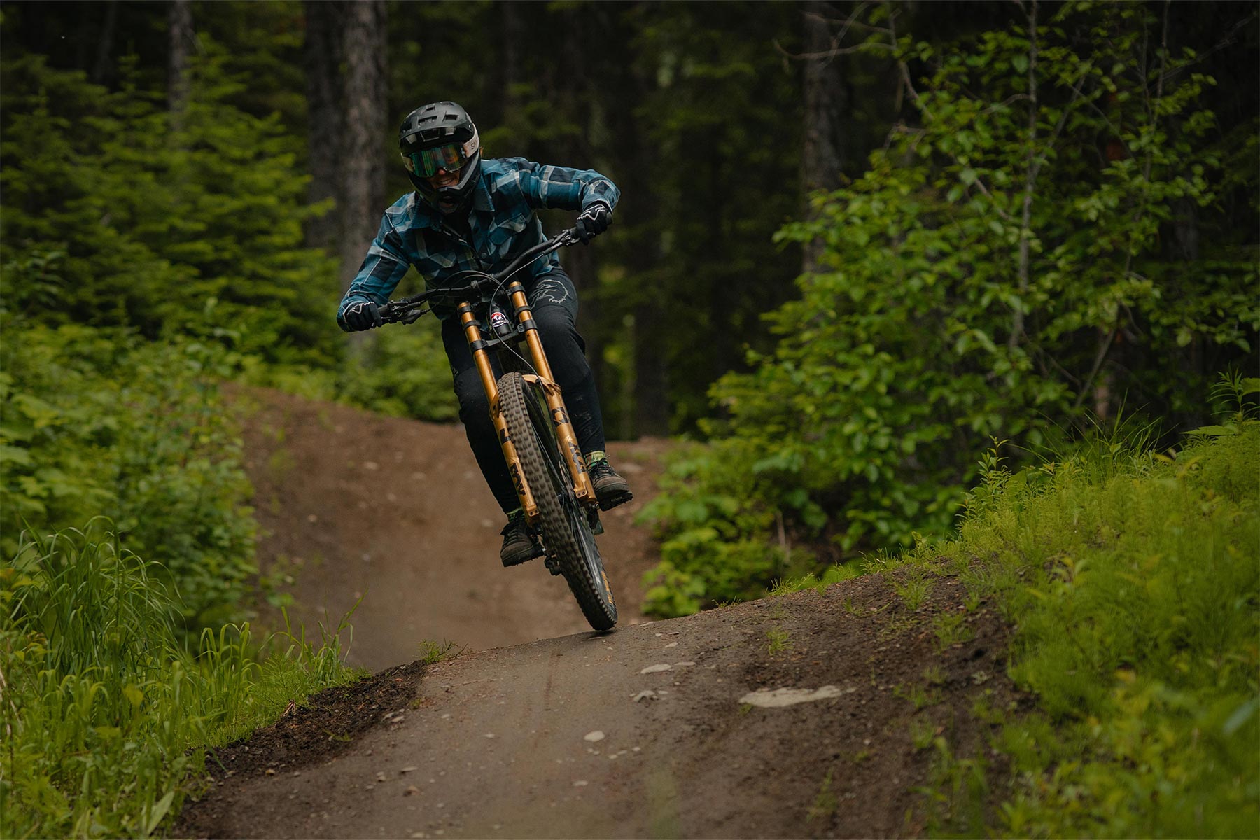 biker riding down a trail with greenery around them
