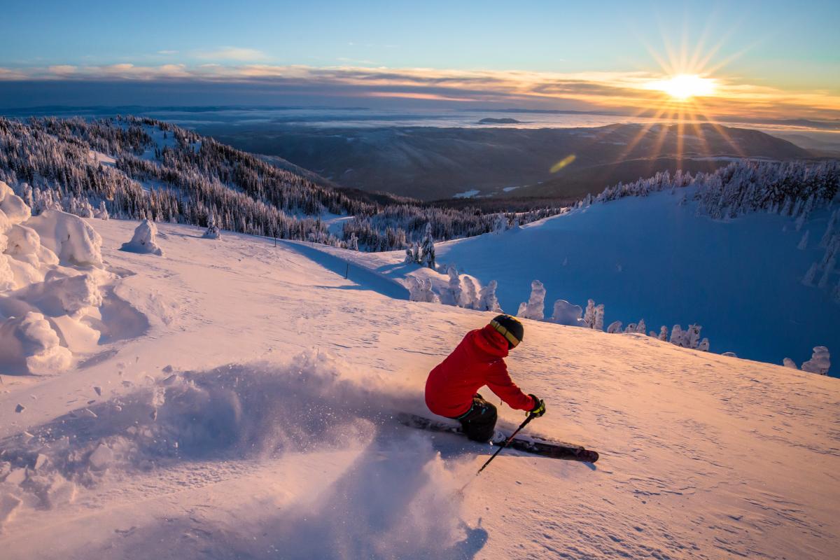 Skier in powder with the sunrise