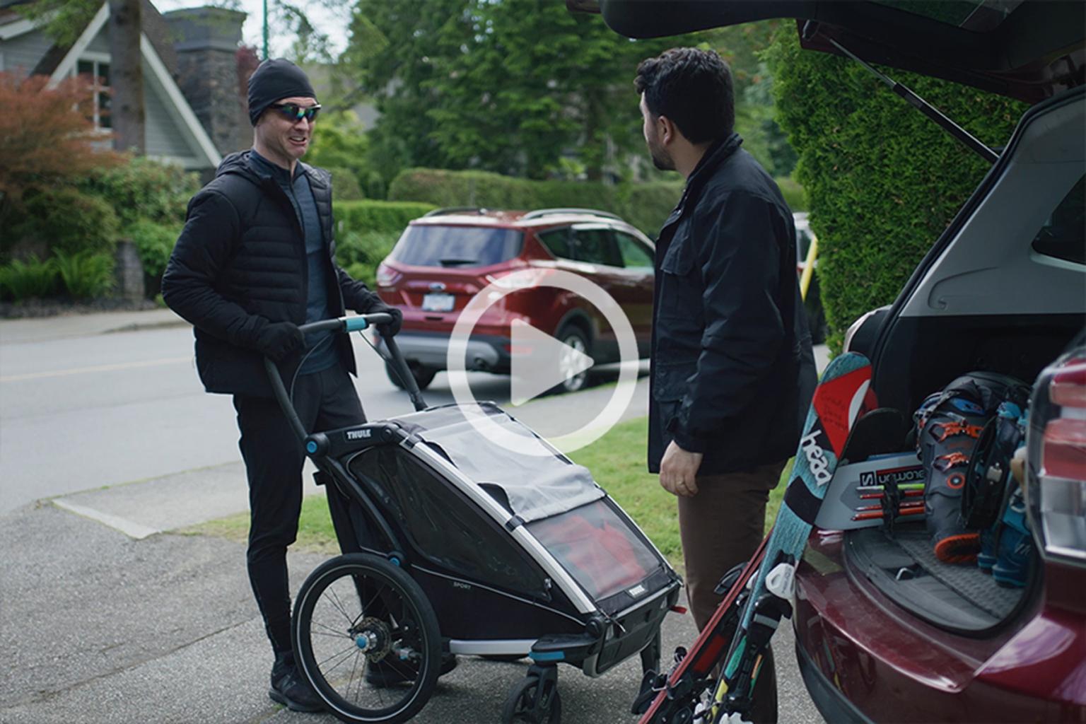 A man with a stroller talking to a man in his drive way