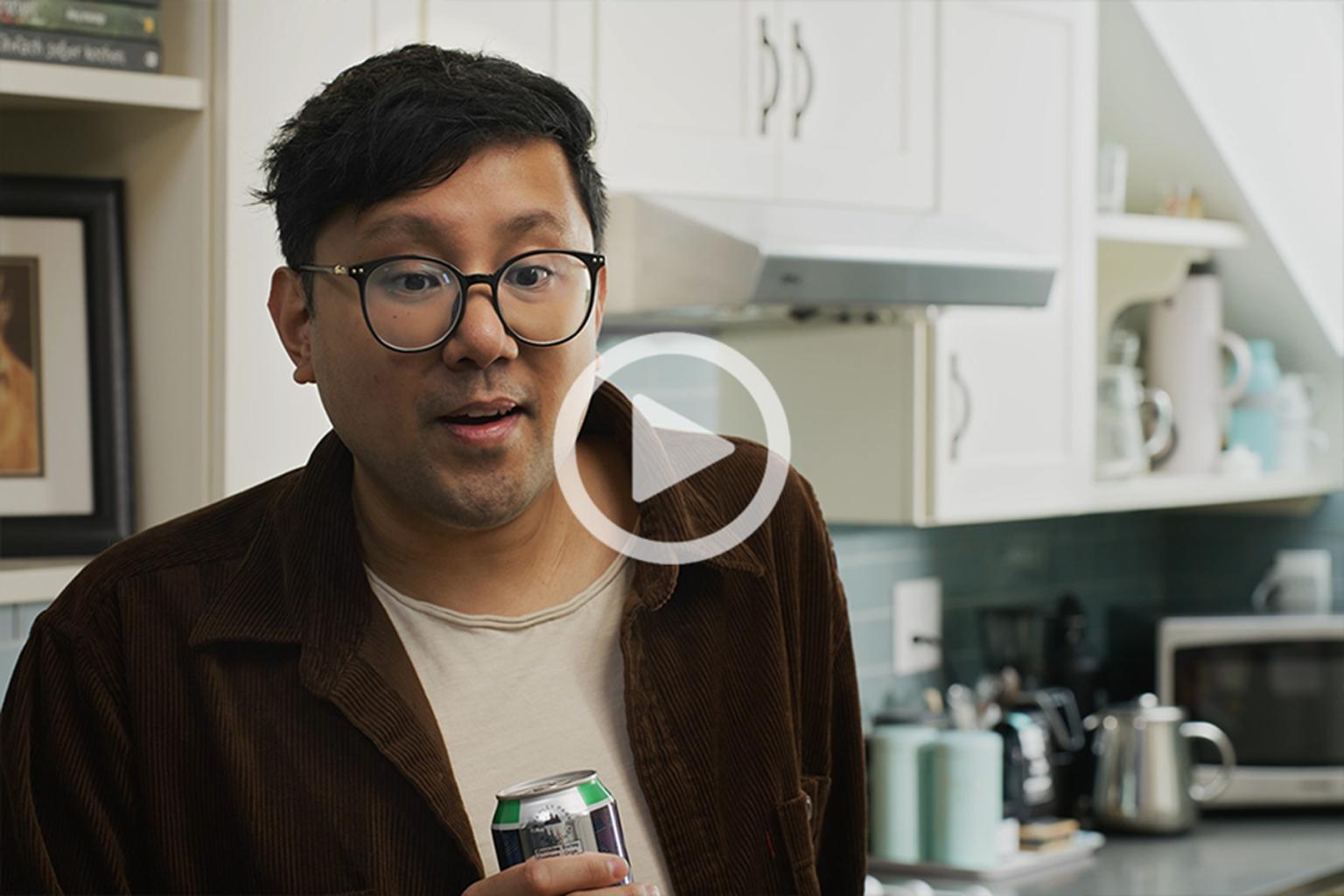 A man holding a drink in a kitchen