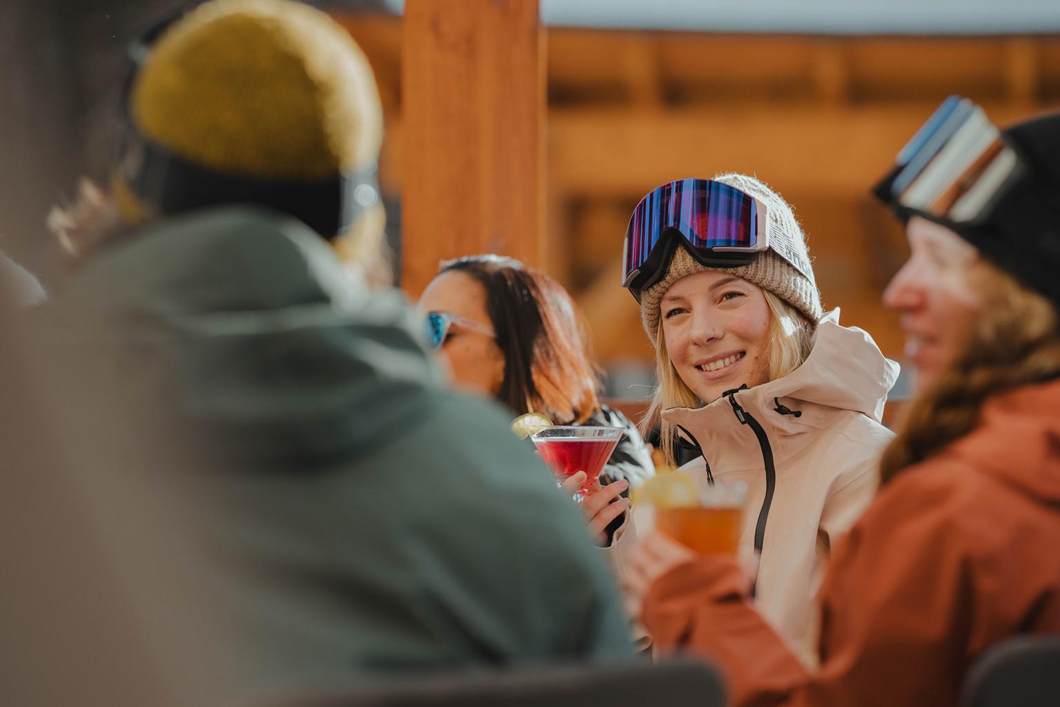 woman holding cocktail with friends on morriseys patio in sun peaks