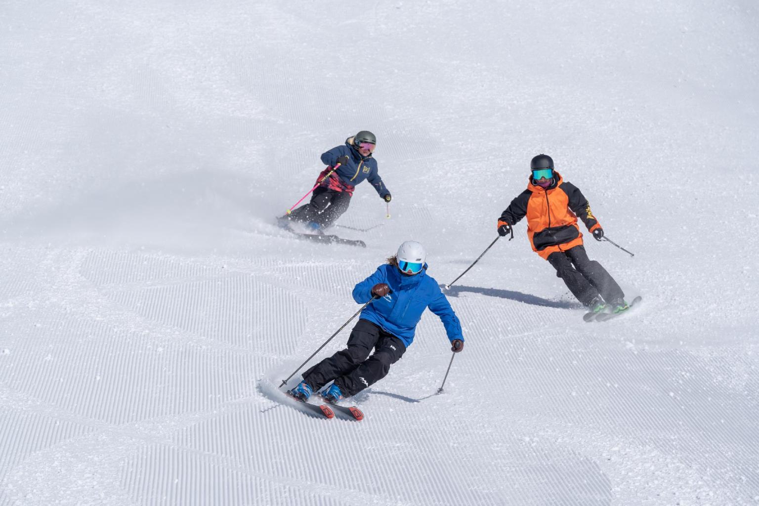 Ski school group lesson with three skiers descending close together
