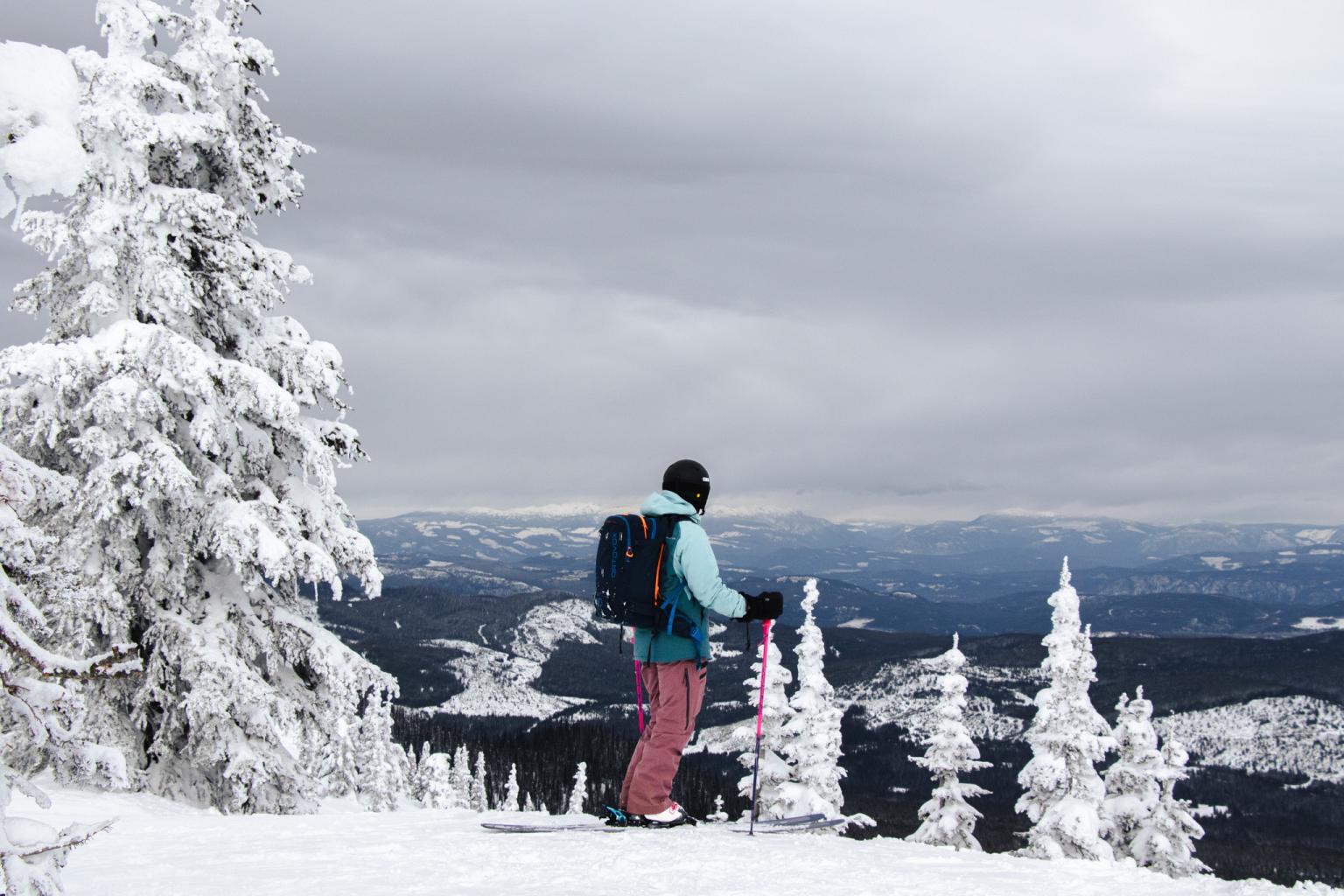 Skier standing on top of mountain looking at mountain scenery from Sun Peaks Resort