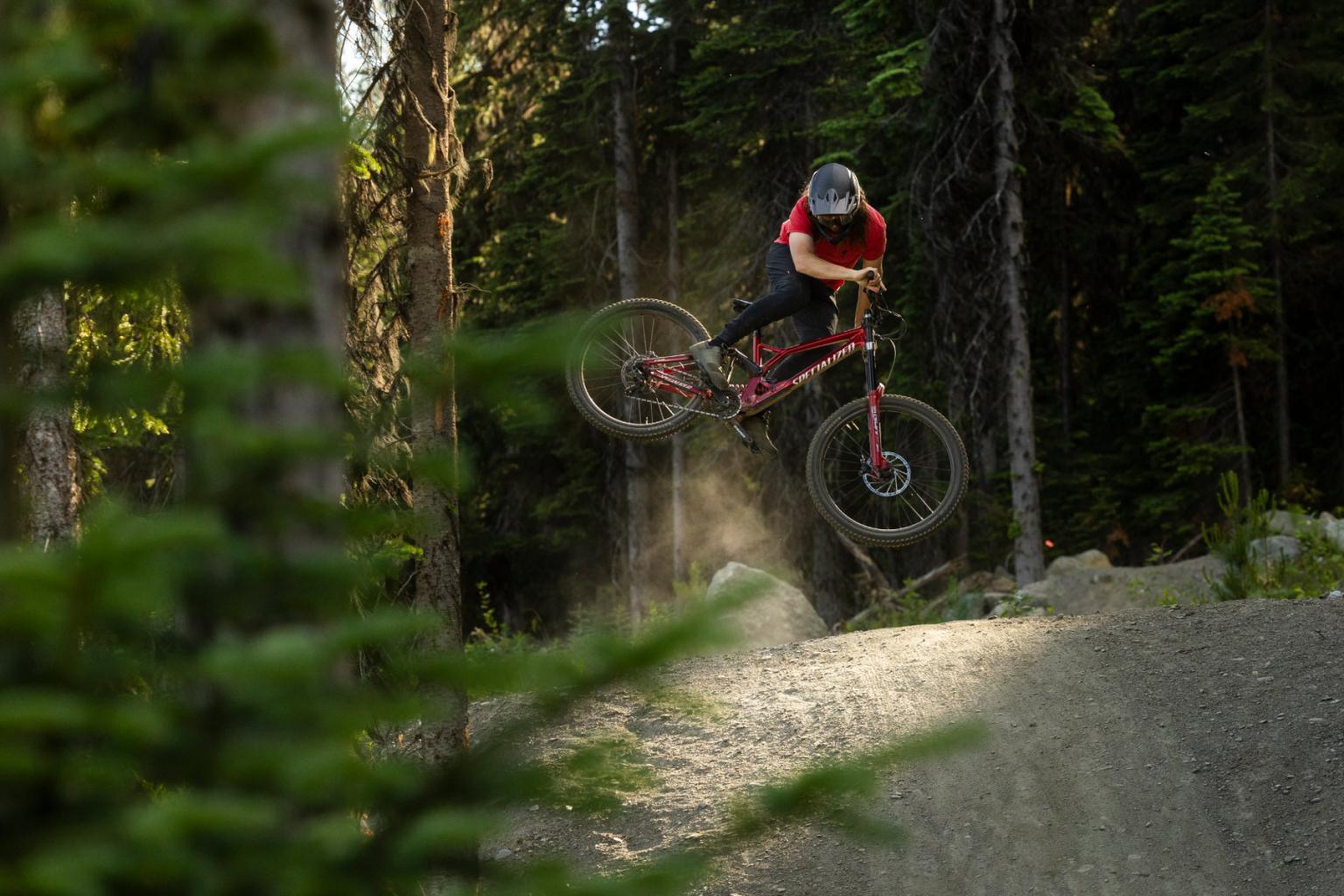 Biker hitting a jump with trees surrounding them