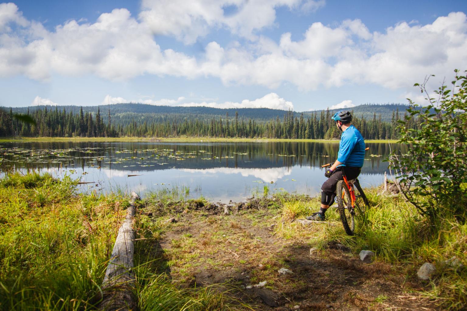 Biker sitting on his bike looking out to a lake 