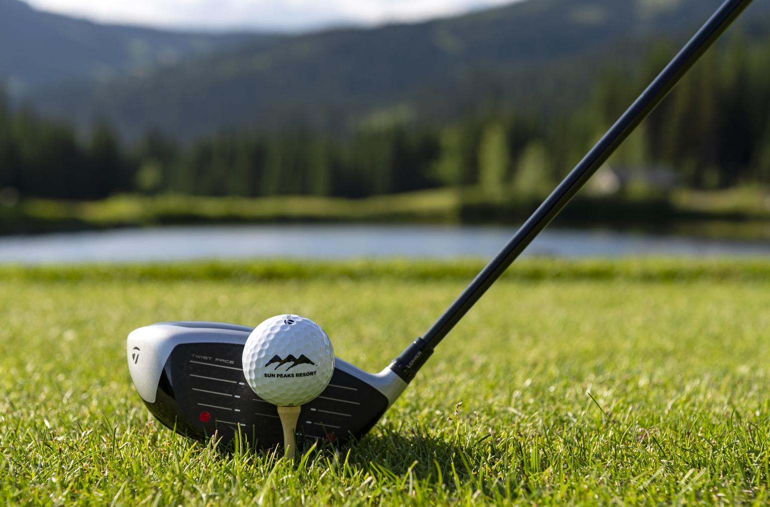 golf club lining up with golf ball on tee over the lake on golf course