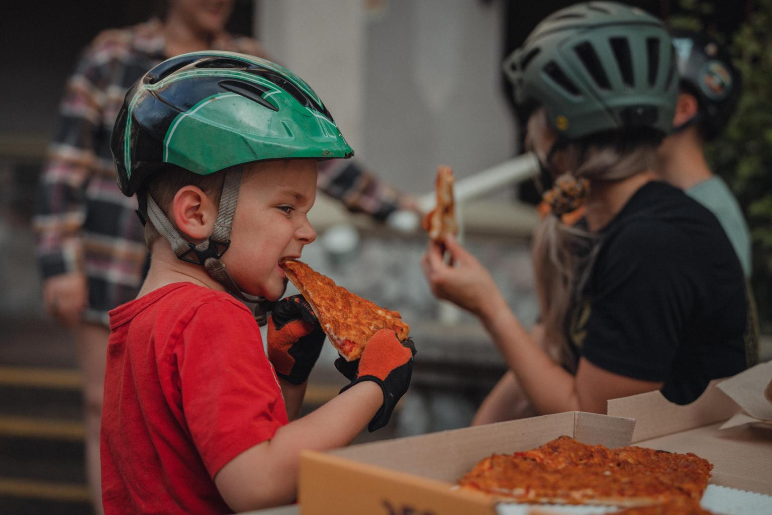 Little boy eating a slice of pizza from Mountain High Pizza 