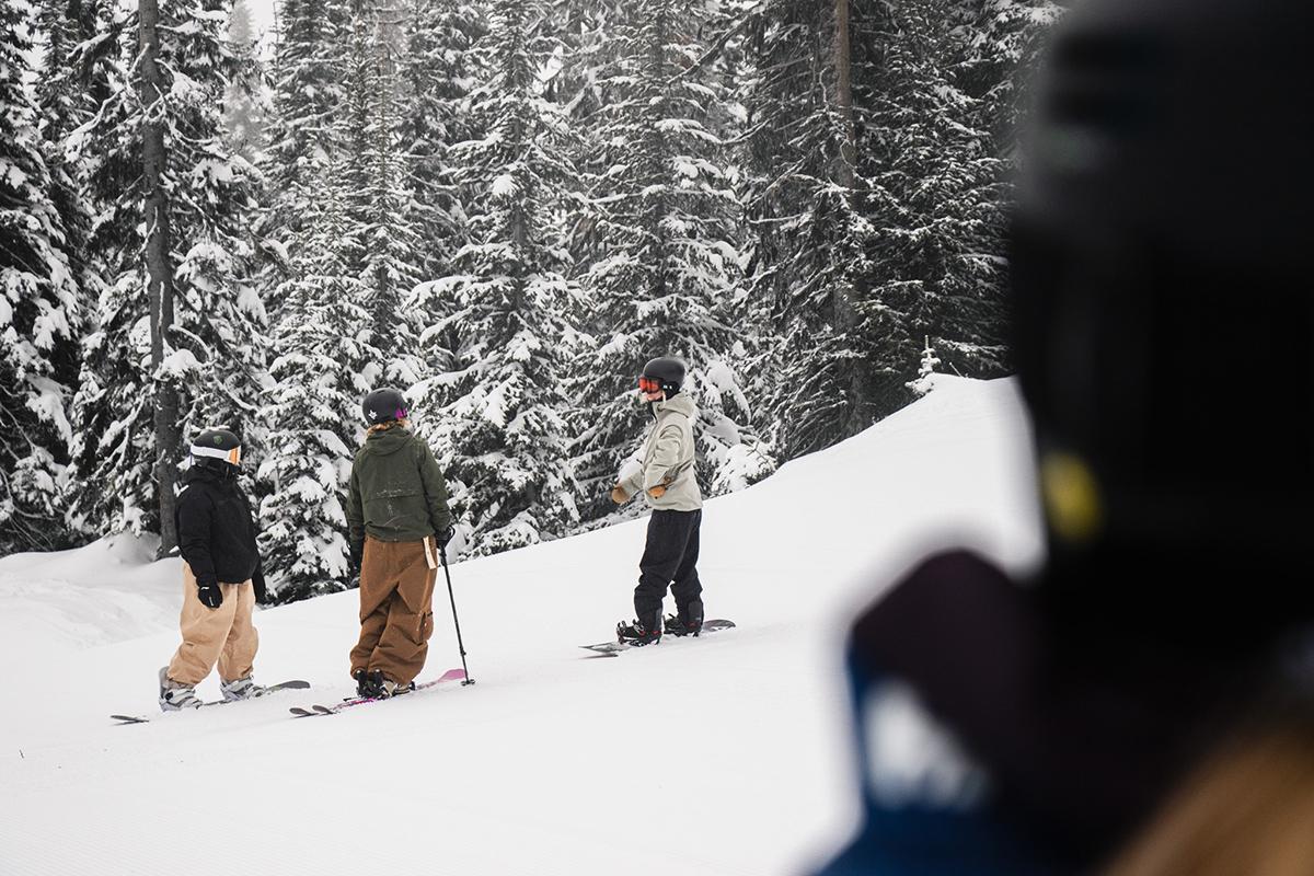 Three members of the Sun Peaks Ambassador Team skiing and snowboarding with snowy trees in the background.