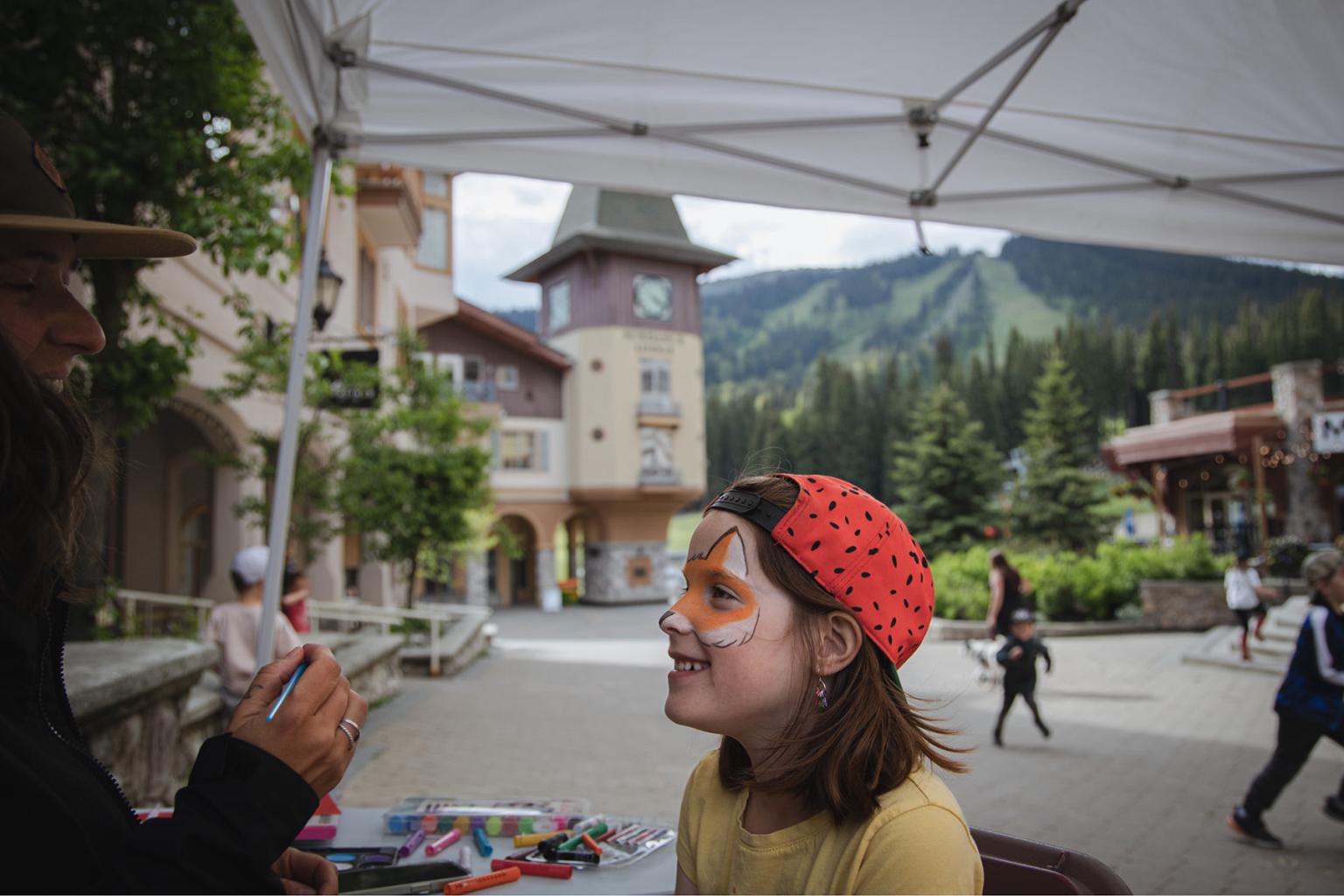 Face painting in sun peaks village with mountain background