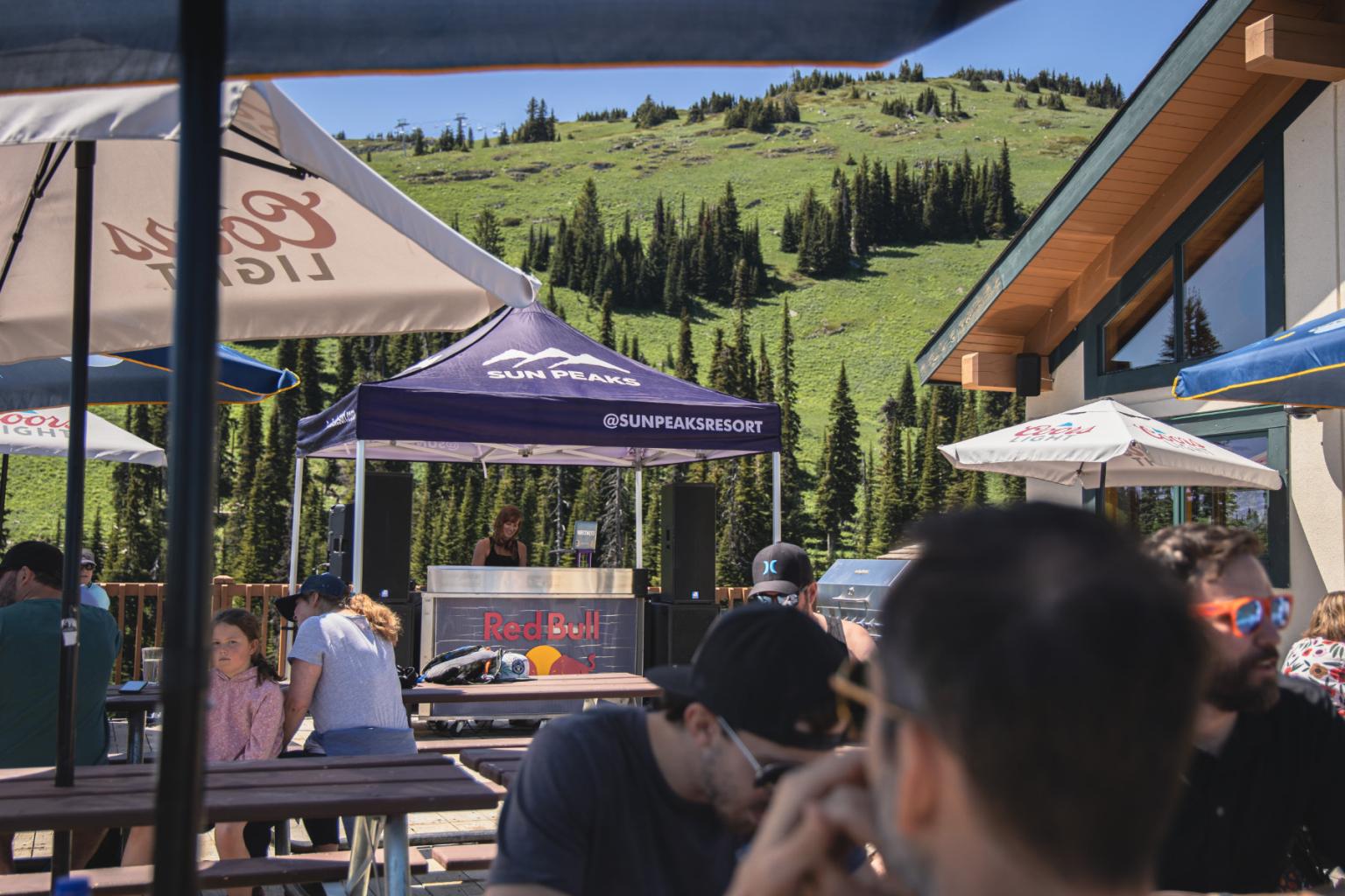 A dj playing music on a patio with people around them and trees in the background