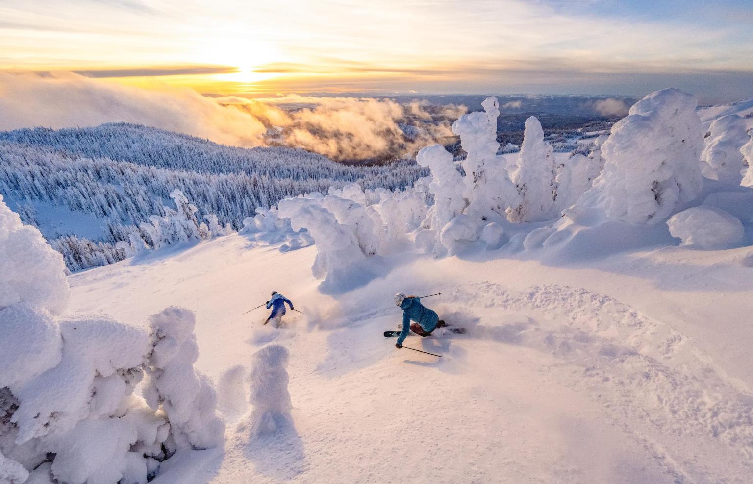 Two skiers descending into the West Bowl in Sun Peaks near sunrise