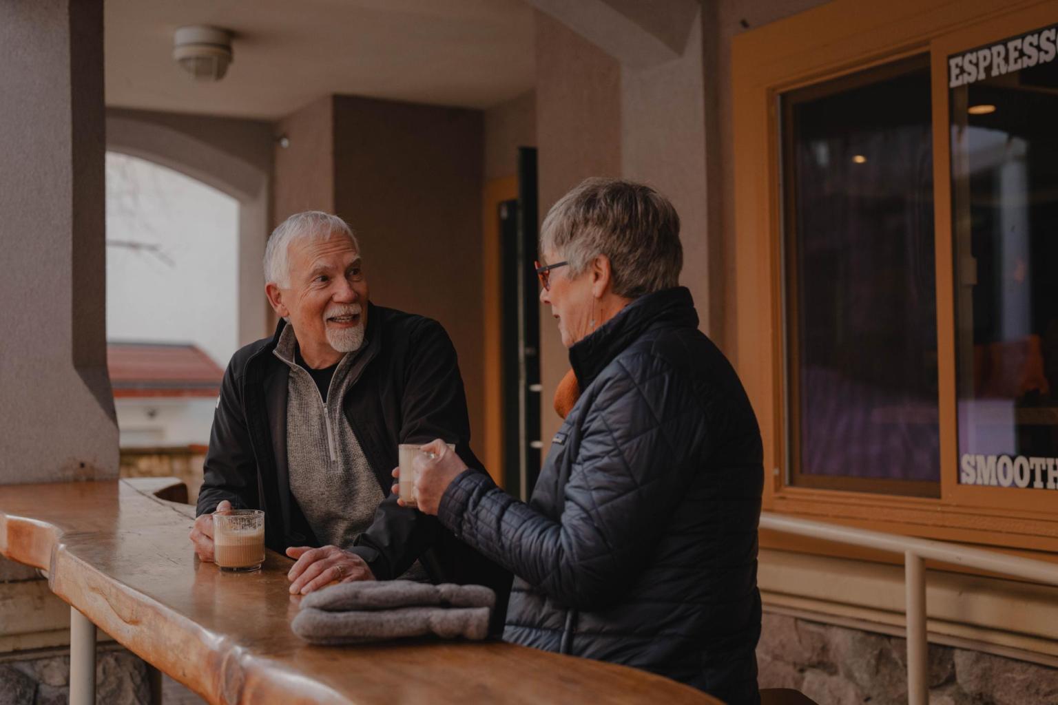 Couple sharing coffee at an outdoor cafe in winter in Sun Peaks village